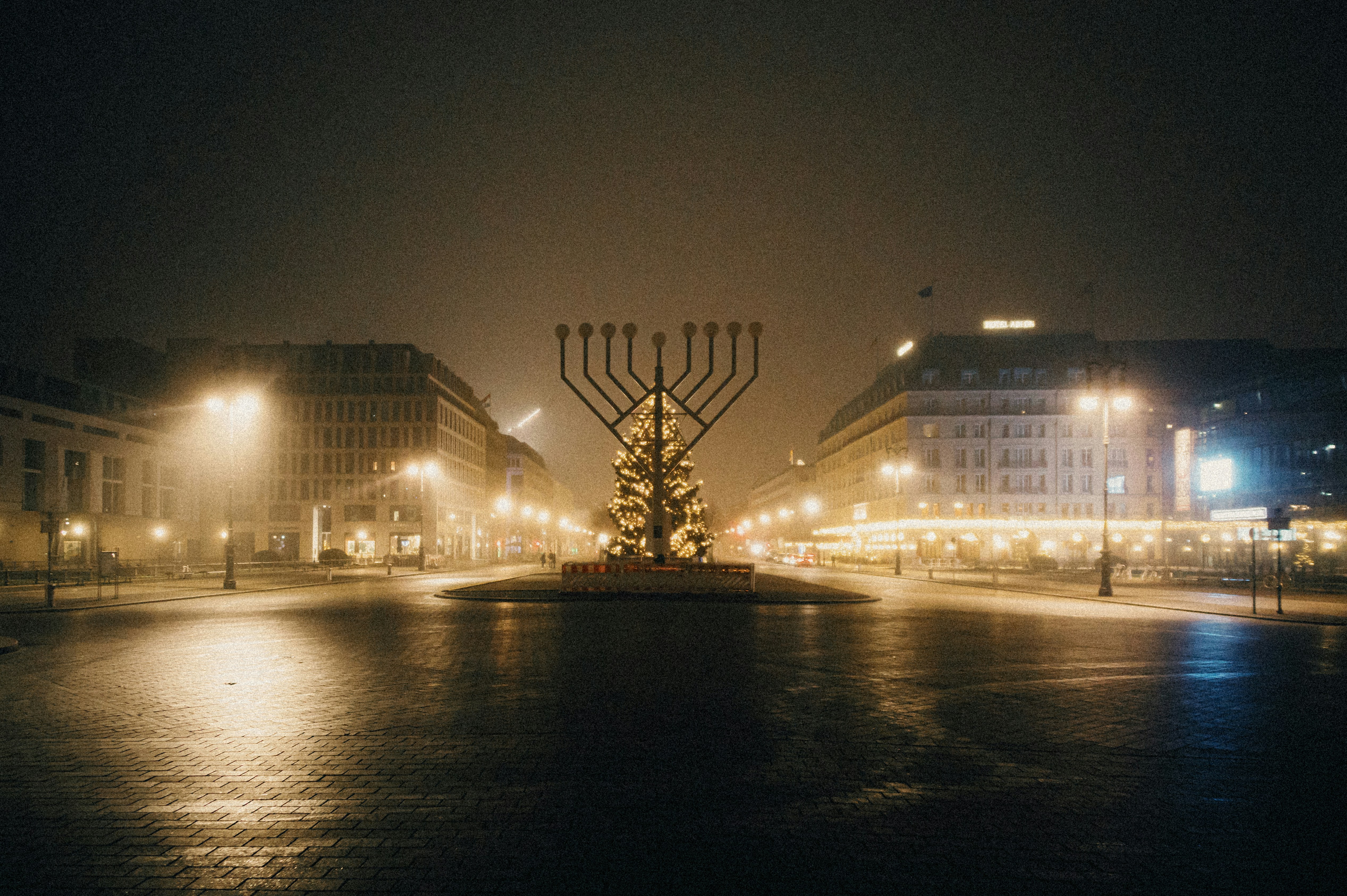 Große Menora, die nachts auf einem nebligen Stadtplatz präsentiert wird