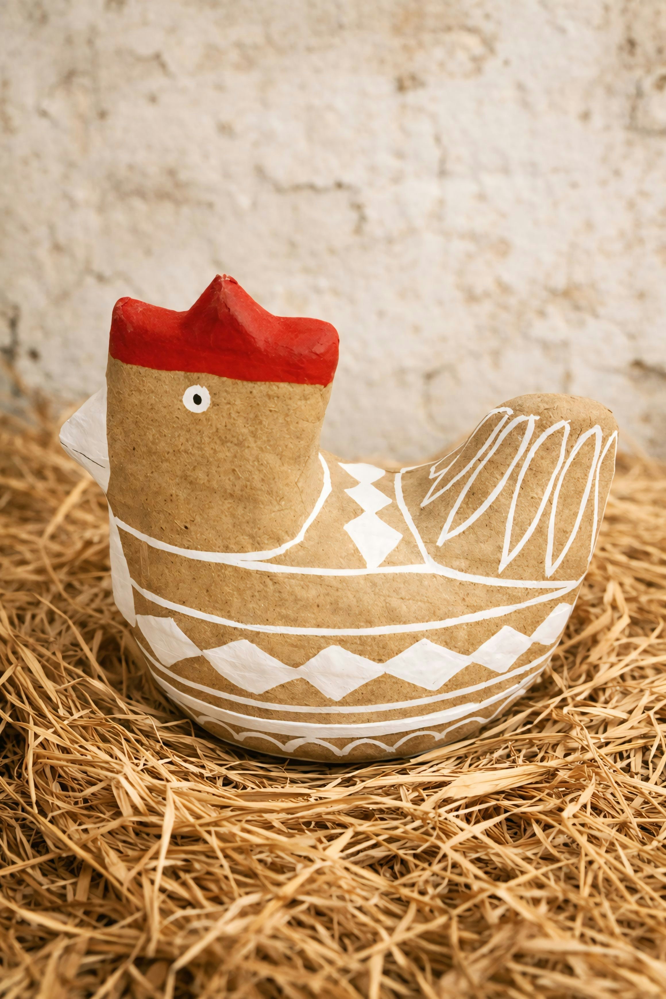 A decorative chicken figurine on a bed of straw