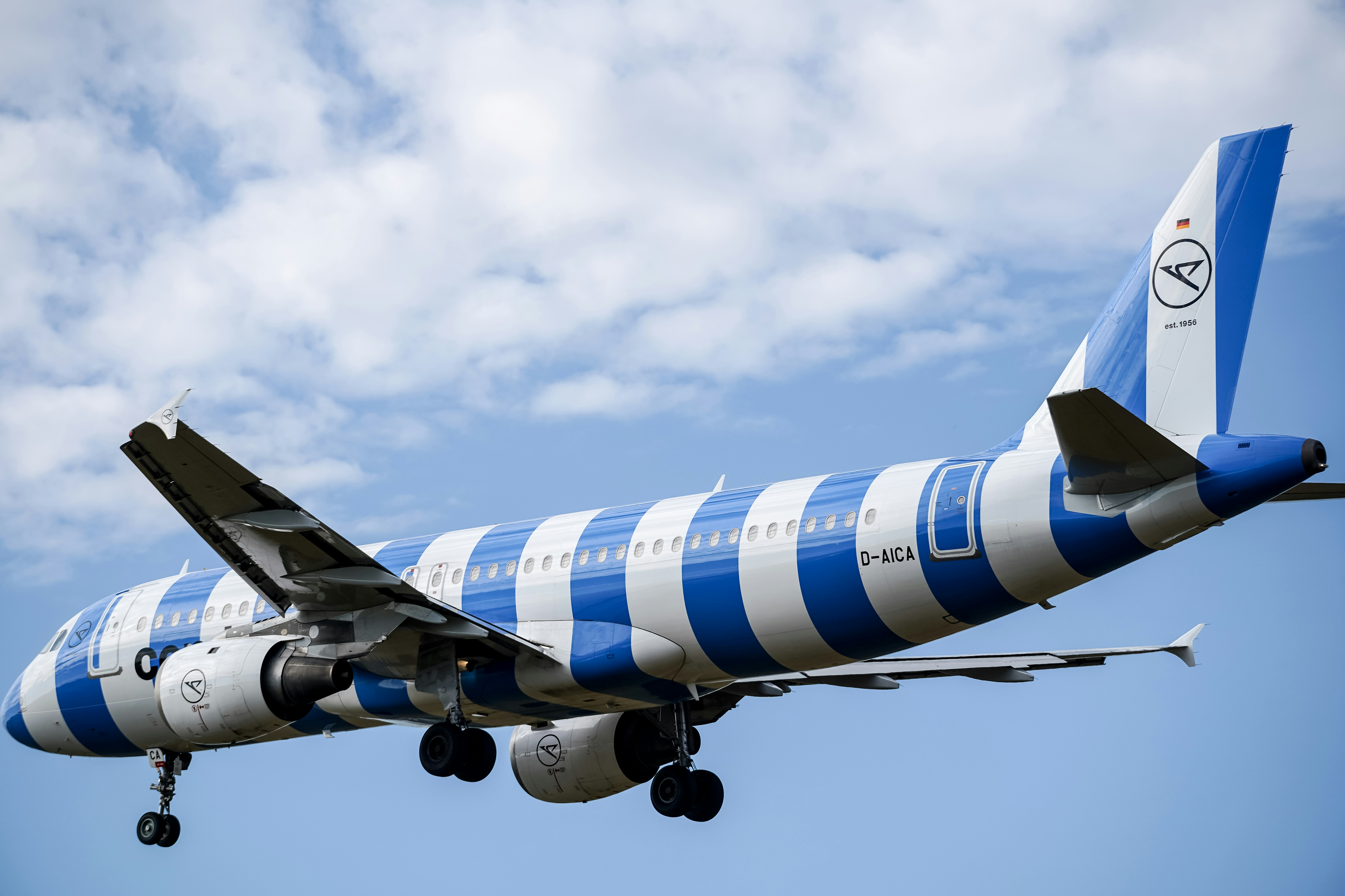 Airplane with blue and white stripes flying in sky