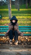 A person bundled up on a park bench in autumn.