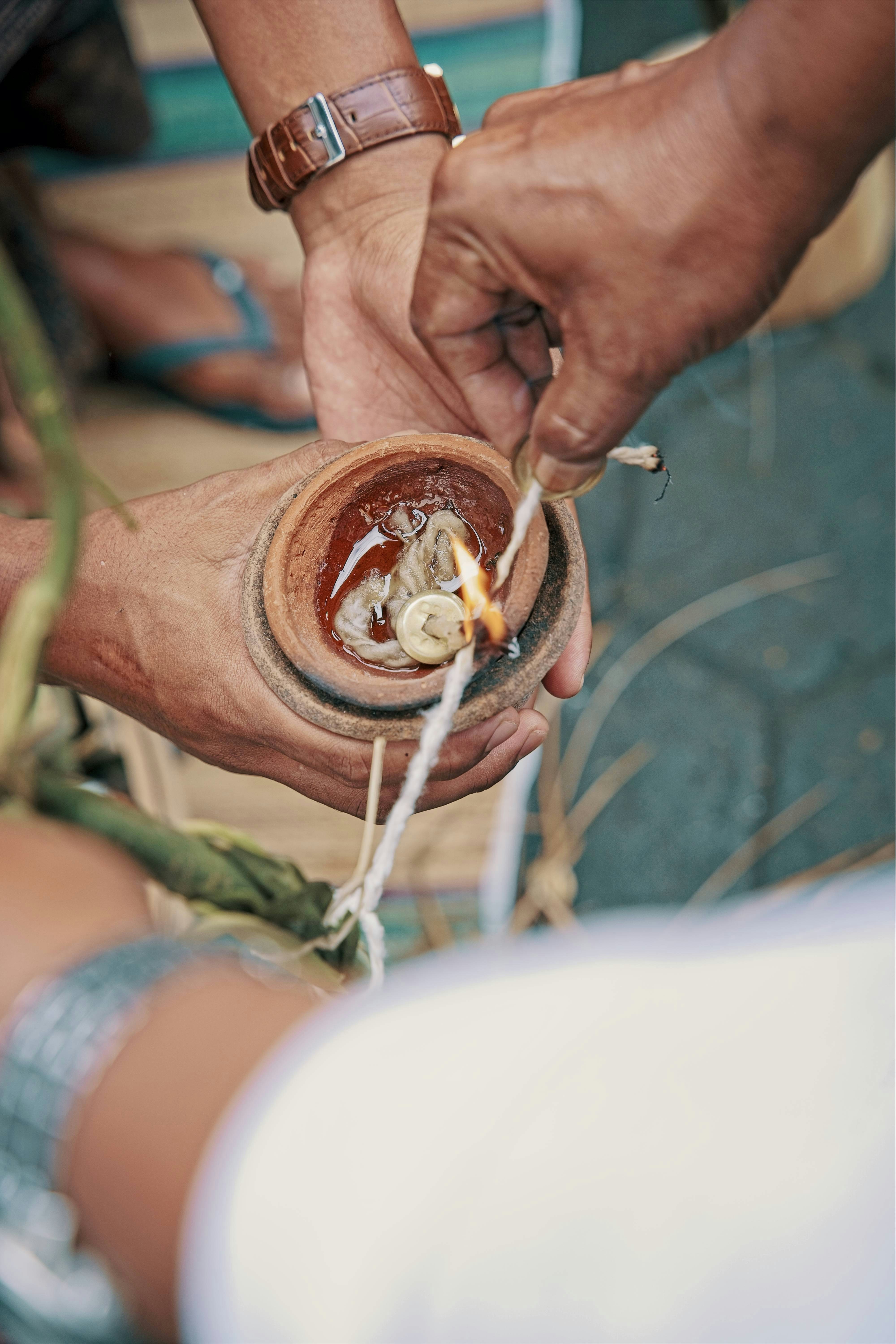 Hands lighting a wick in a clay pot