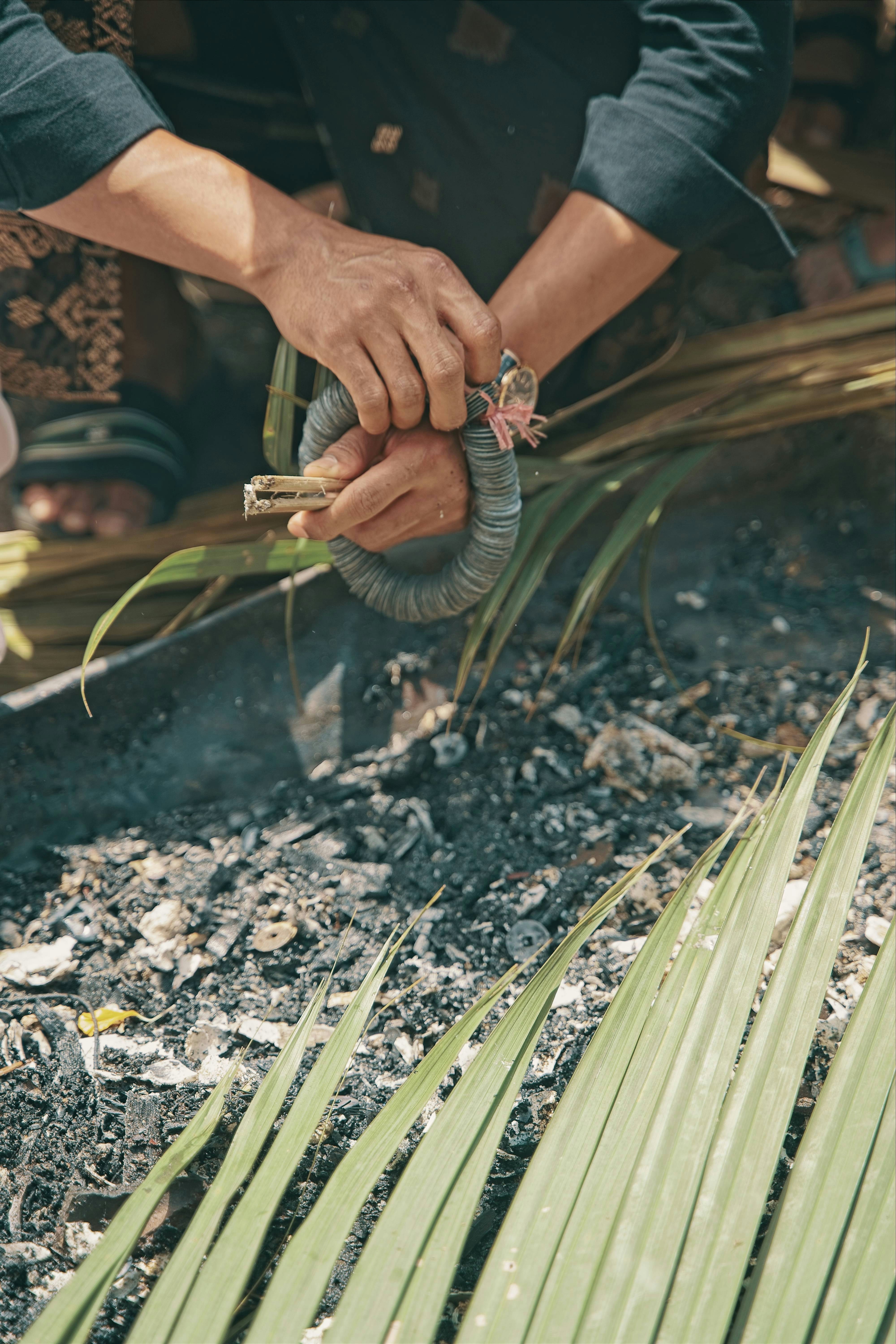Hands wrapping a bundle of incense sticks with string.