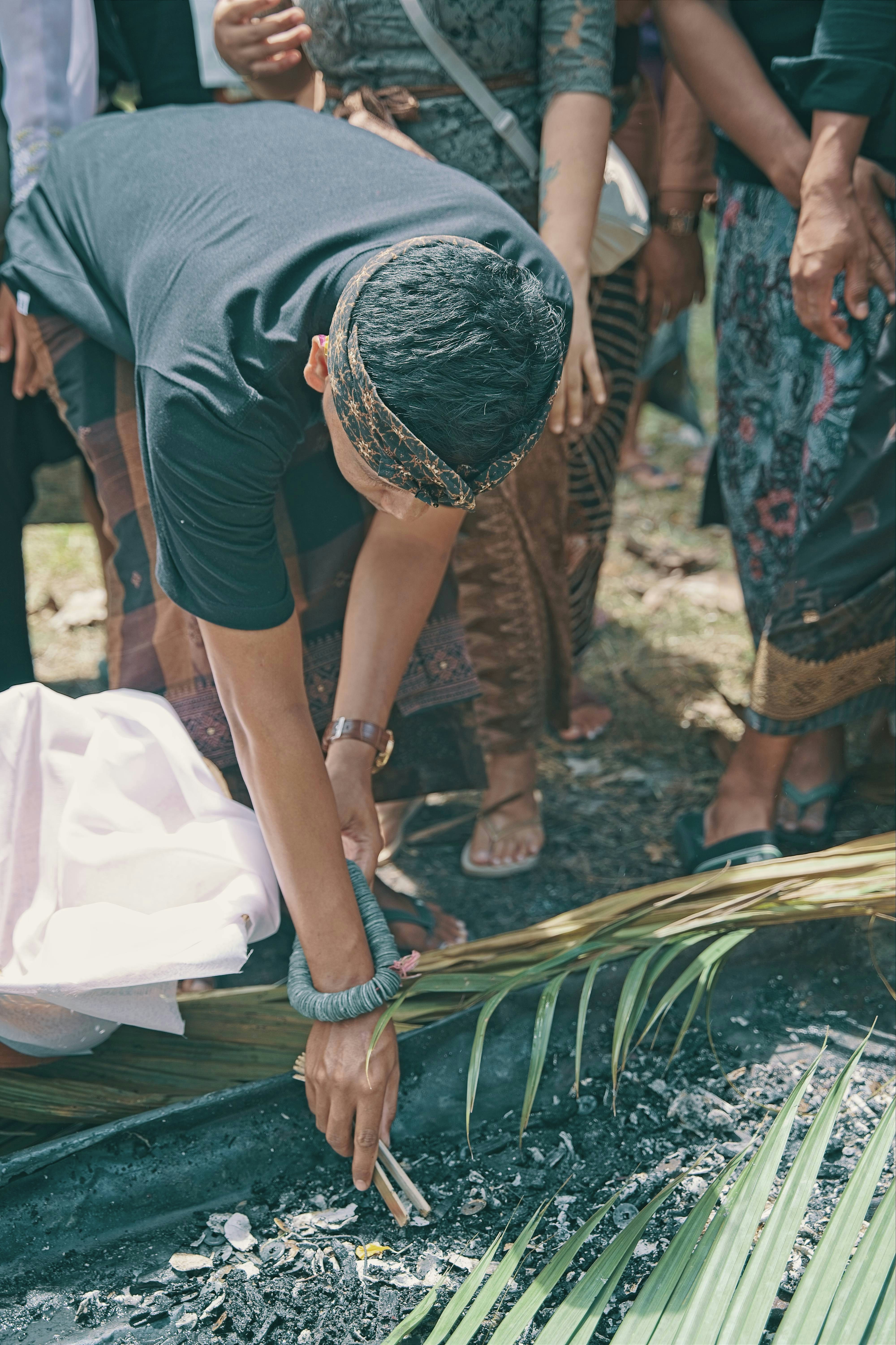 Man in traditional attire performs ritual with fire and leaves