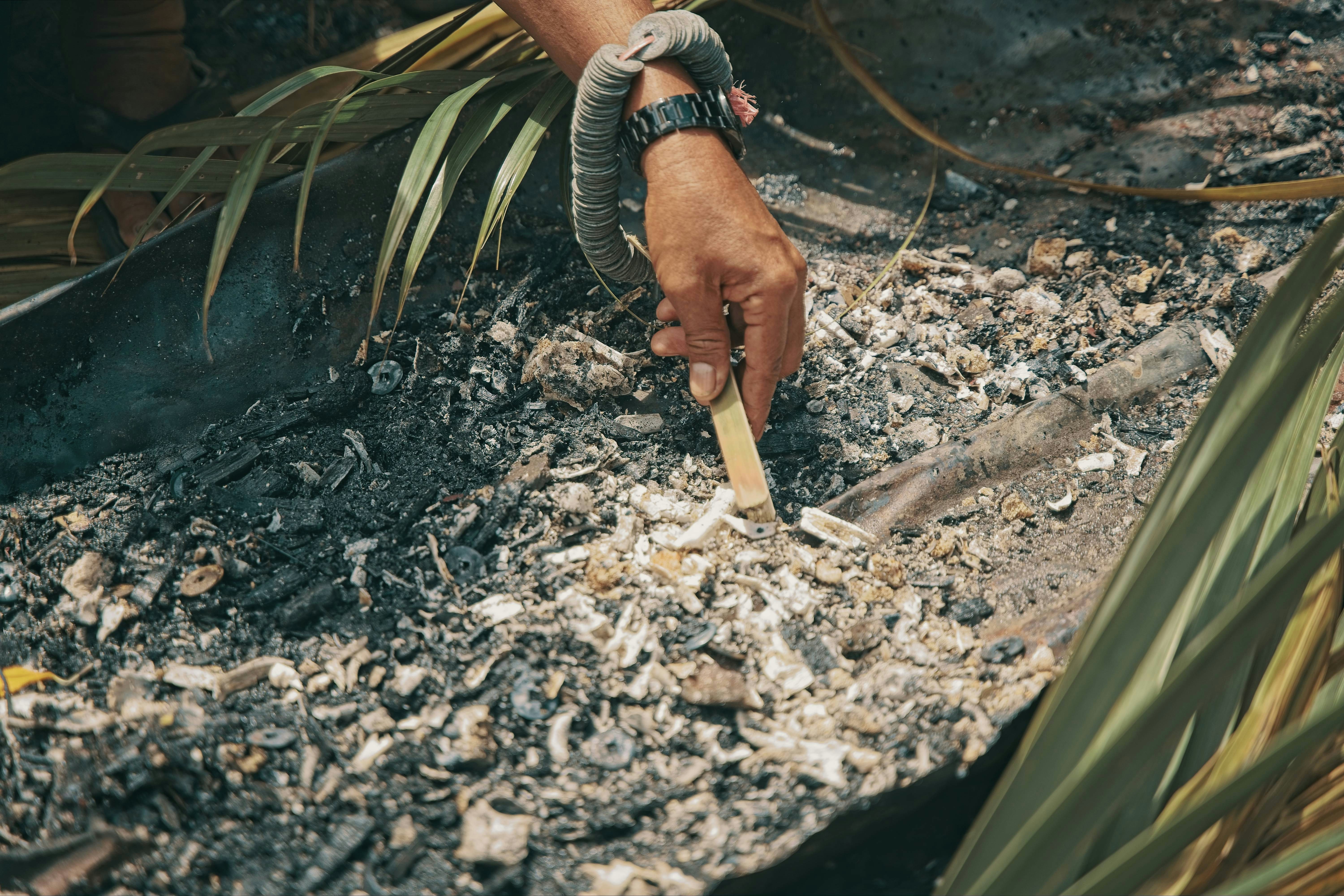 Hand sifting through ashes with a stick