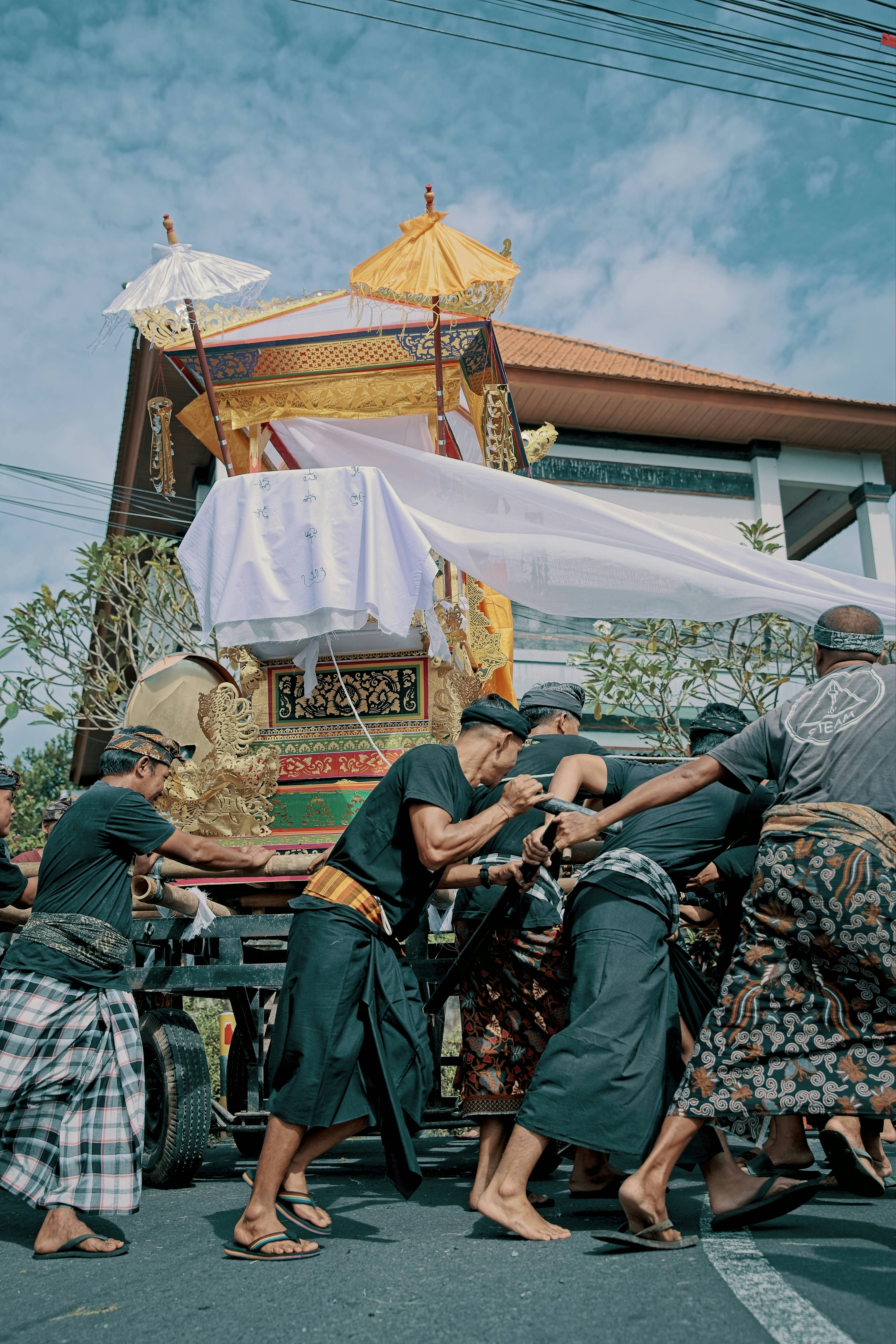 Men carry ornate golden chariot during a procession.