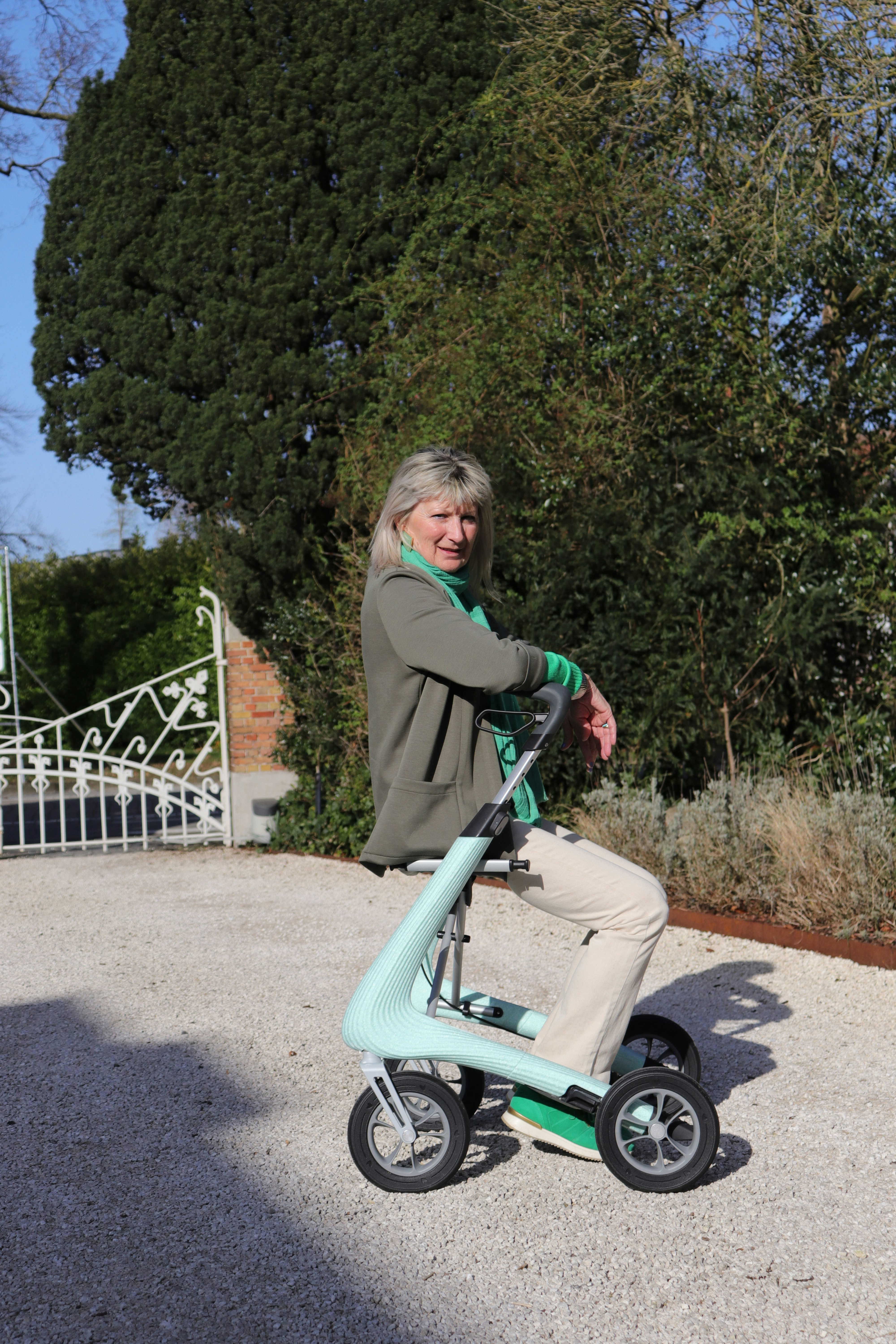 Woman sitting on a light blue mobility scooter outdoors