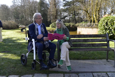 Elderly man in wheelchair shows woman a pink item