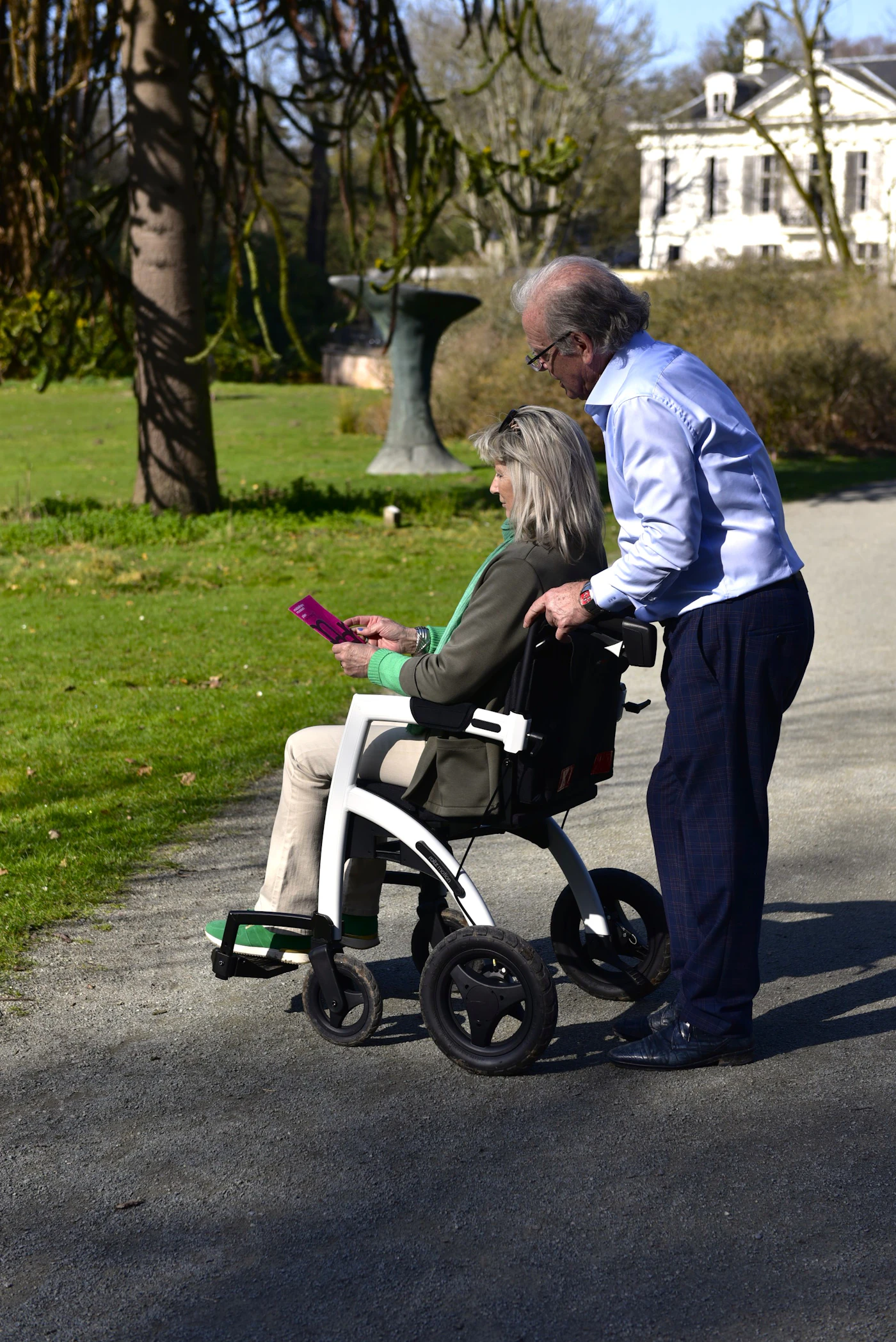 Senior wheelchair passenger receiving mobility assistance outdoors