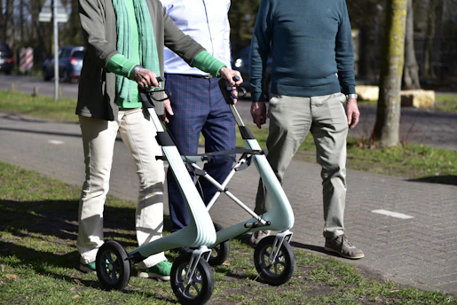 Three people walking with a walker outdoors