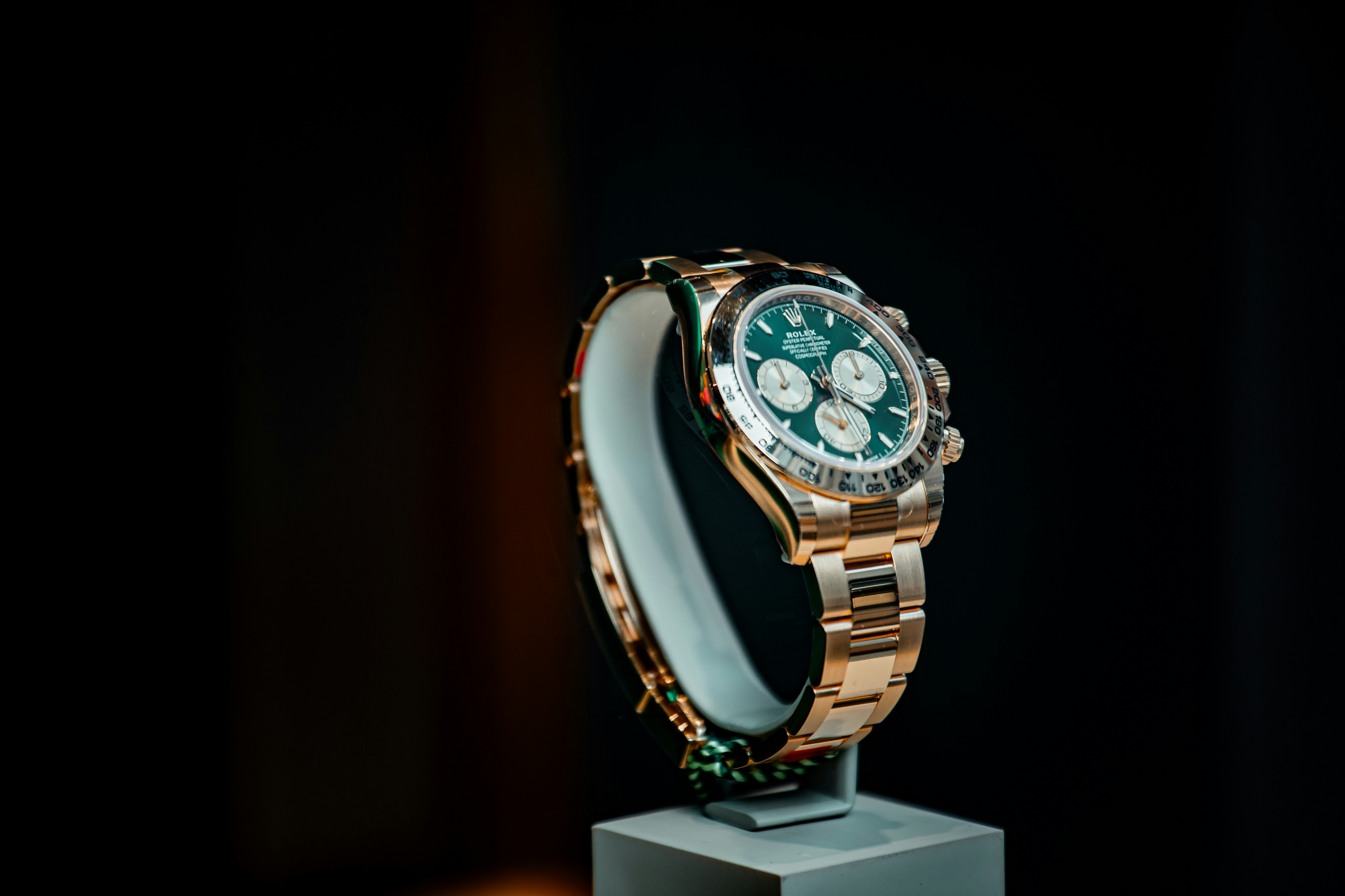 Rose gold luxury watch with green dial on display.