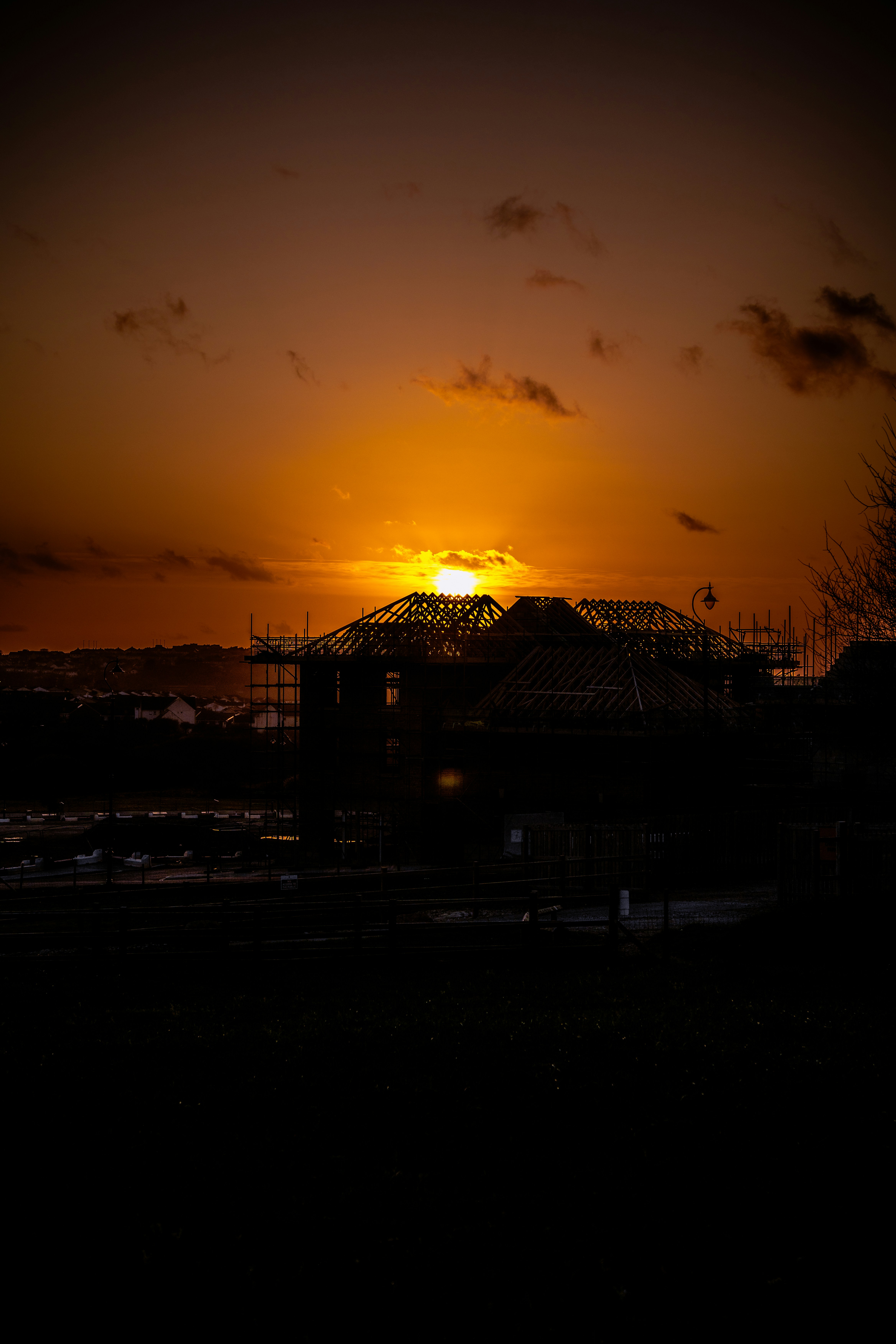 Sunset over a silhouetted building under construction.