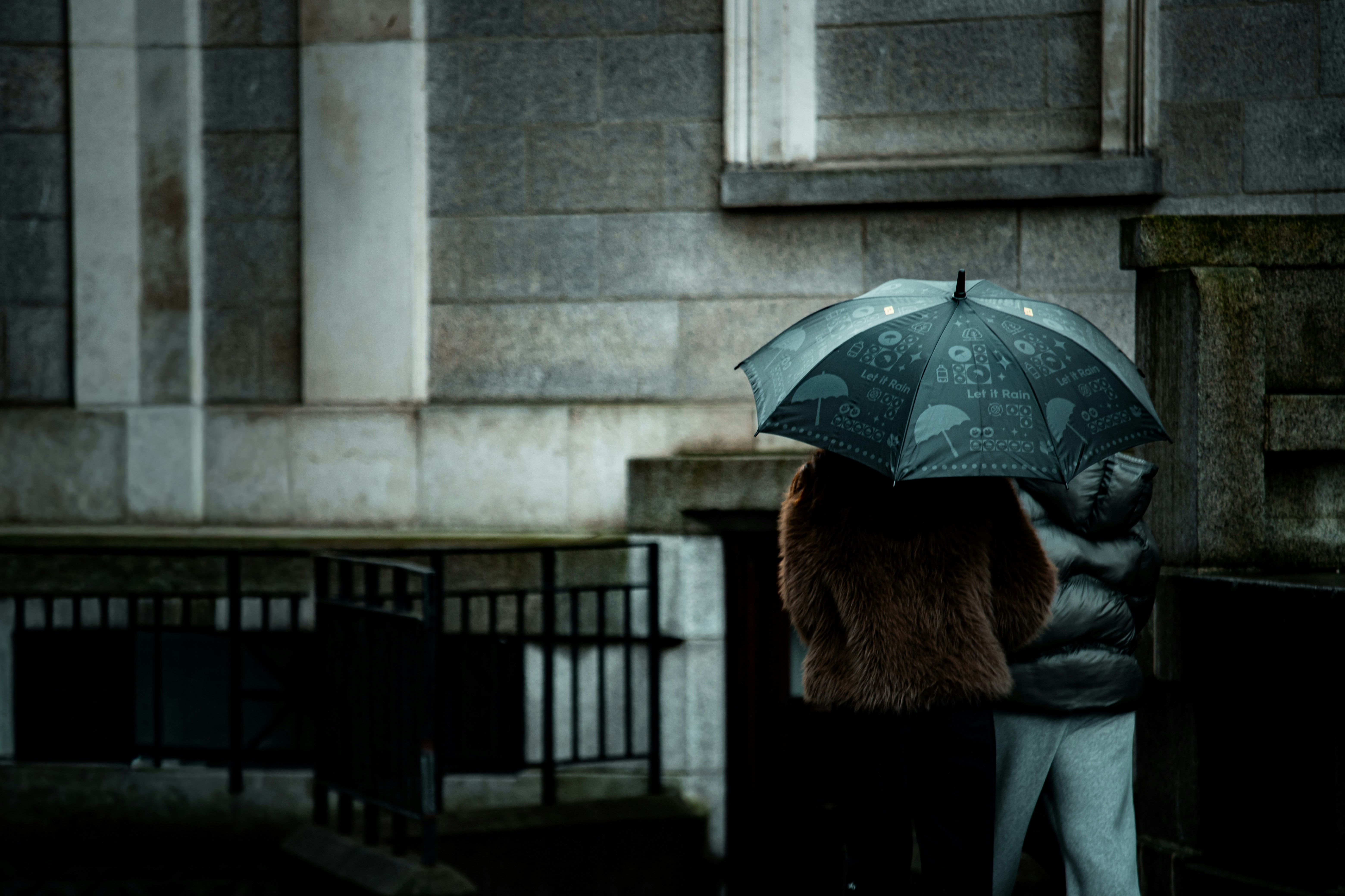 Two people share an umbrella in the rain.