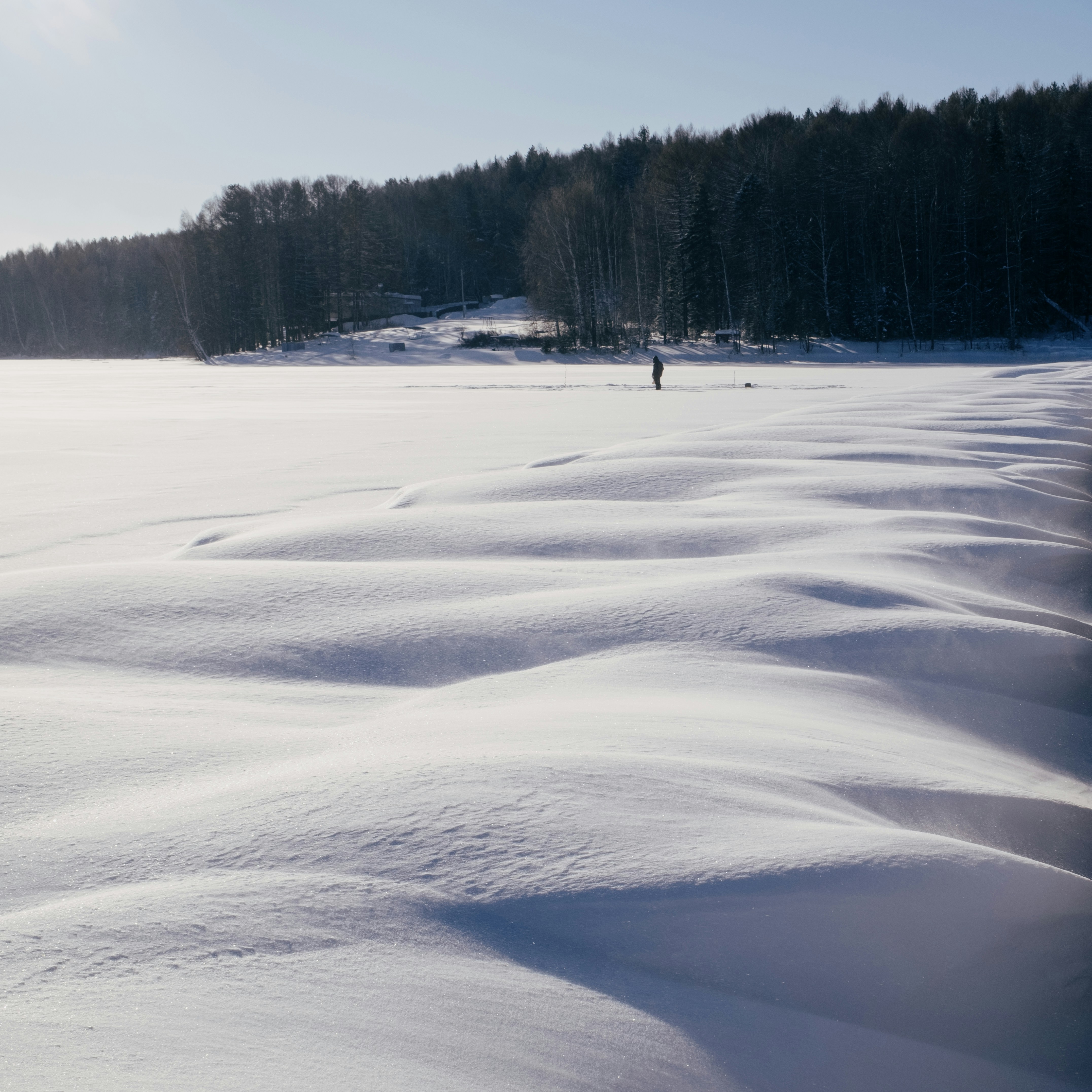 A lone figure walks across a snowy landscape.
