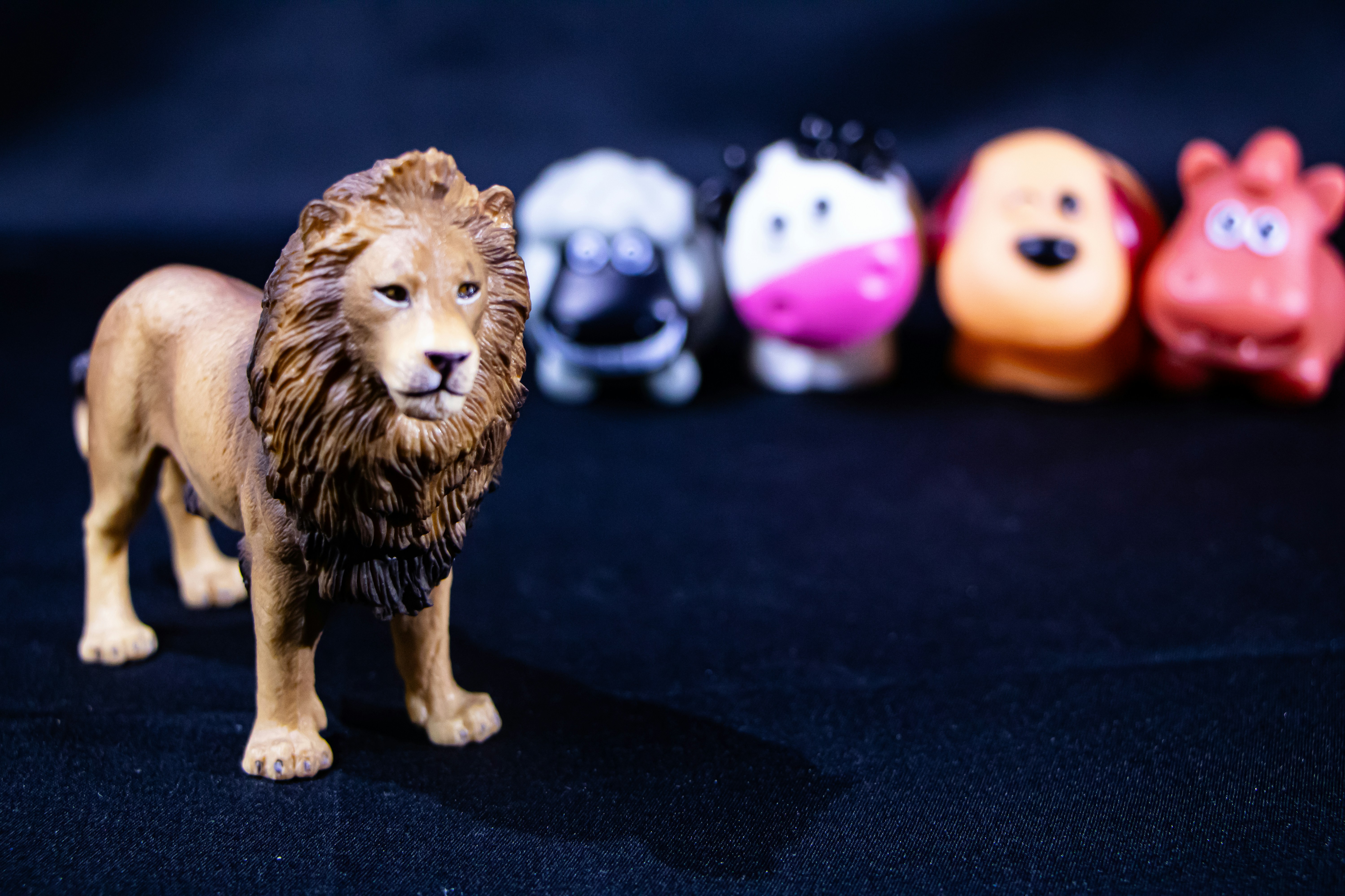 A lion figurine stands in front of toy farm animals.