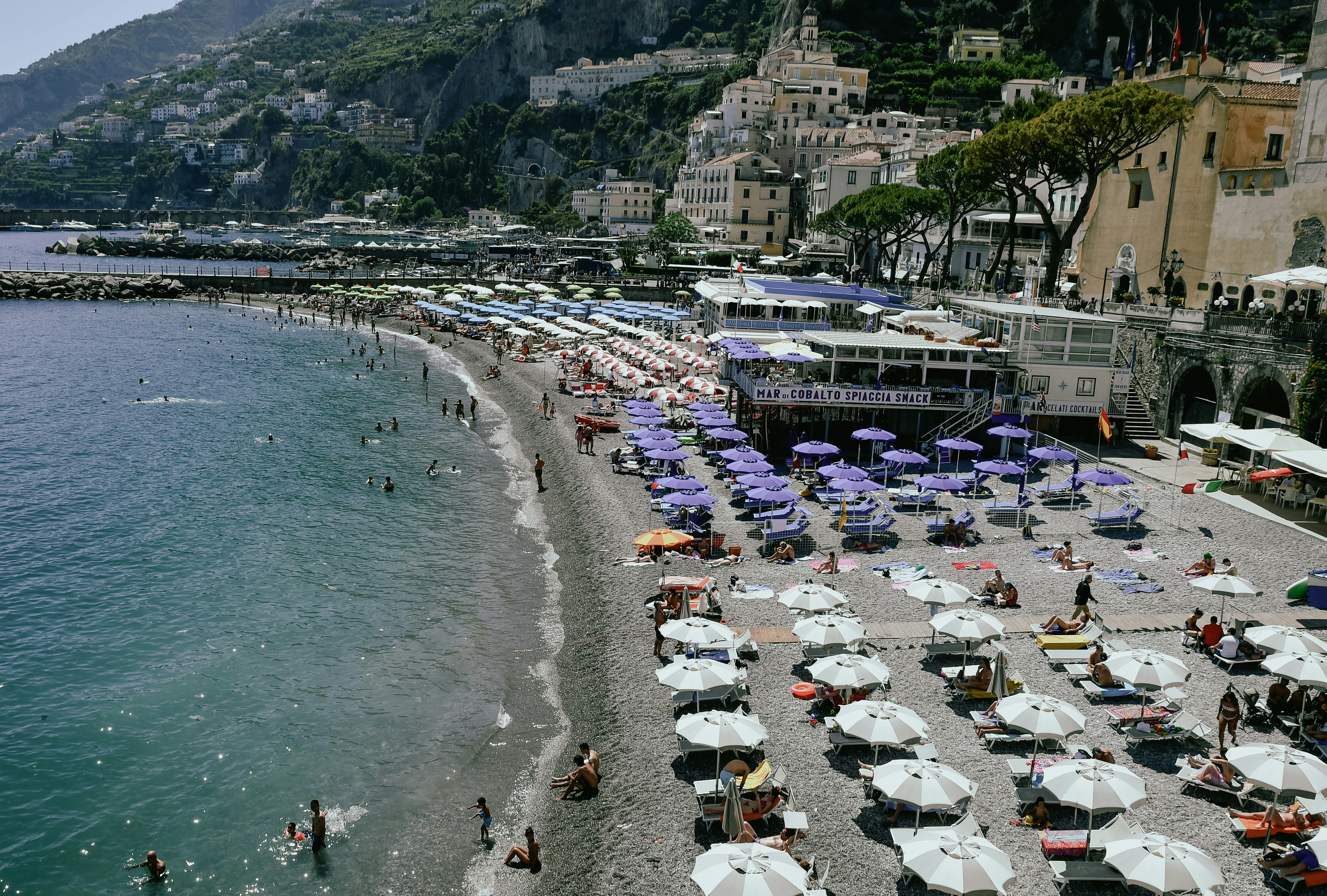 A crowded beach with umbrellas and buildings on a hill
