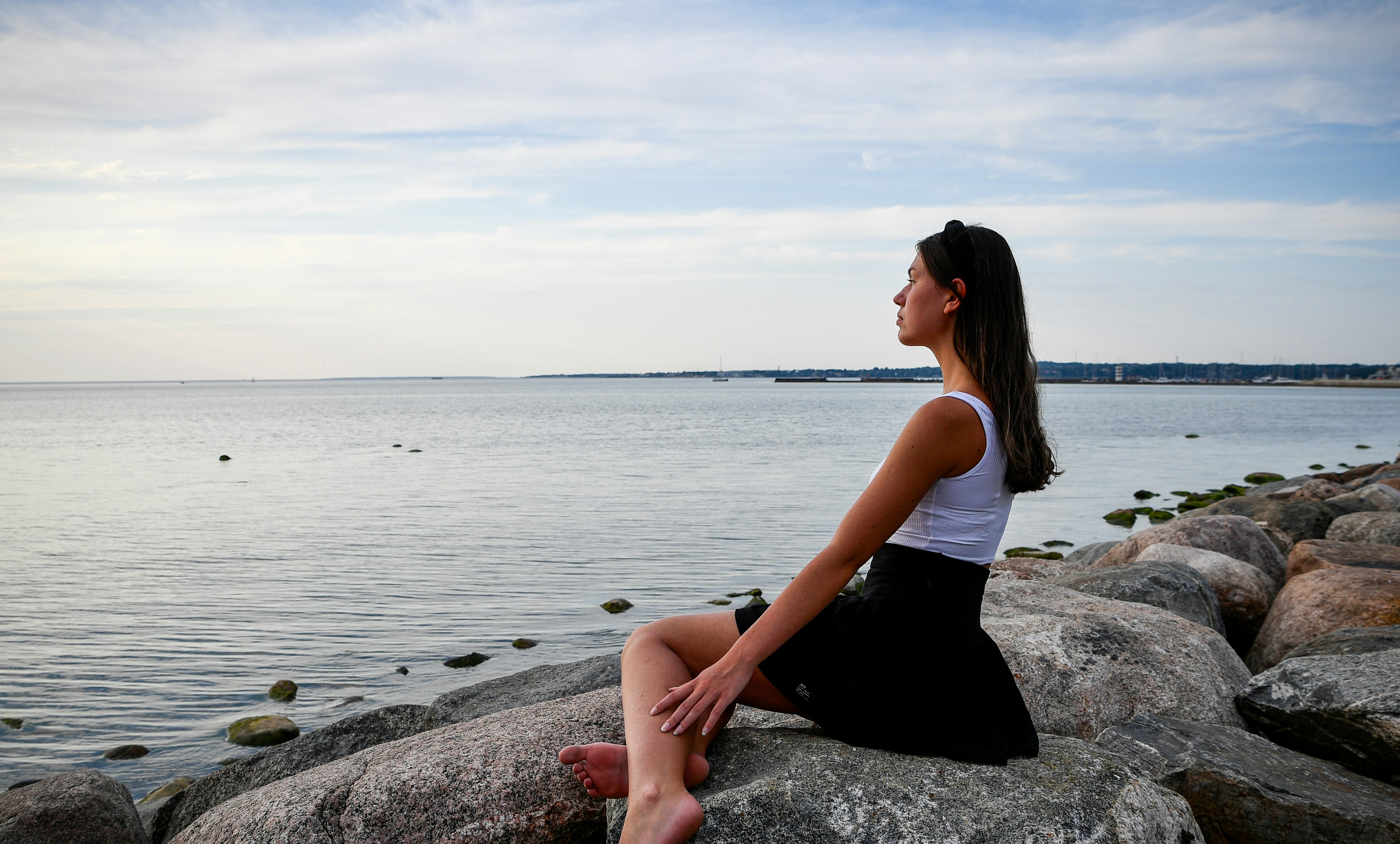 Young woman sitting on rocks by the ocean