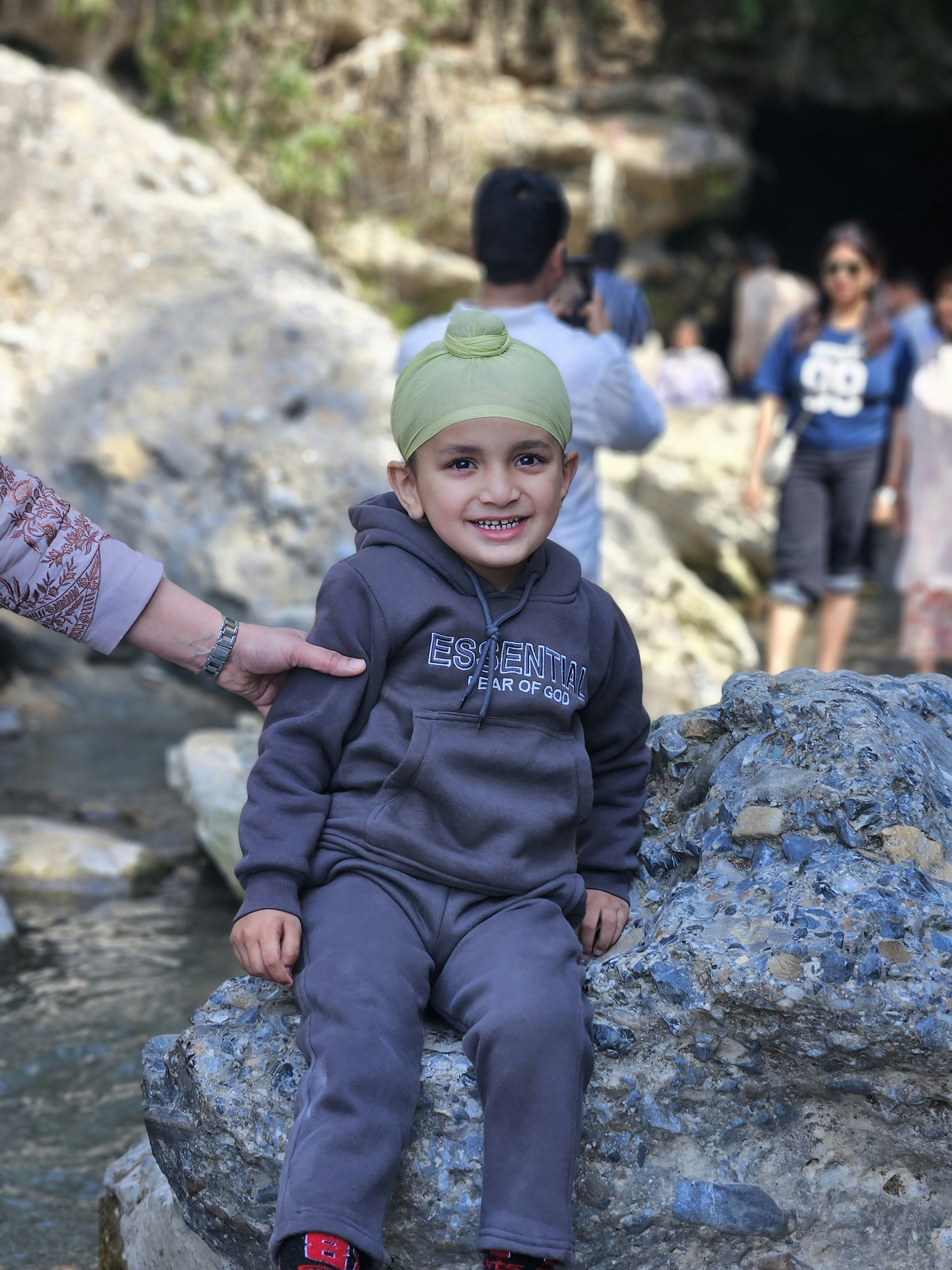Young boy wearing a turban smiles by a stream