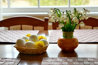 Basket of eggs and vase of flowers on table