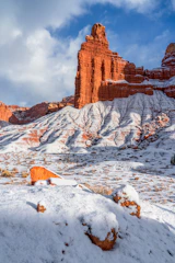 Red rock formations dusted with snow under blue sky.
