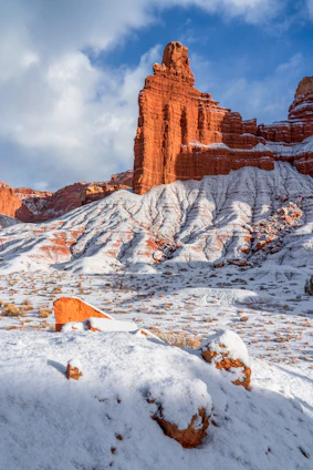 Red rock formations dusted with snow under blue sky.