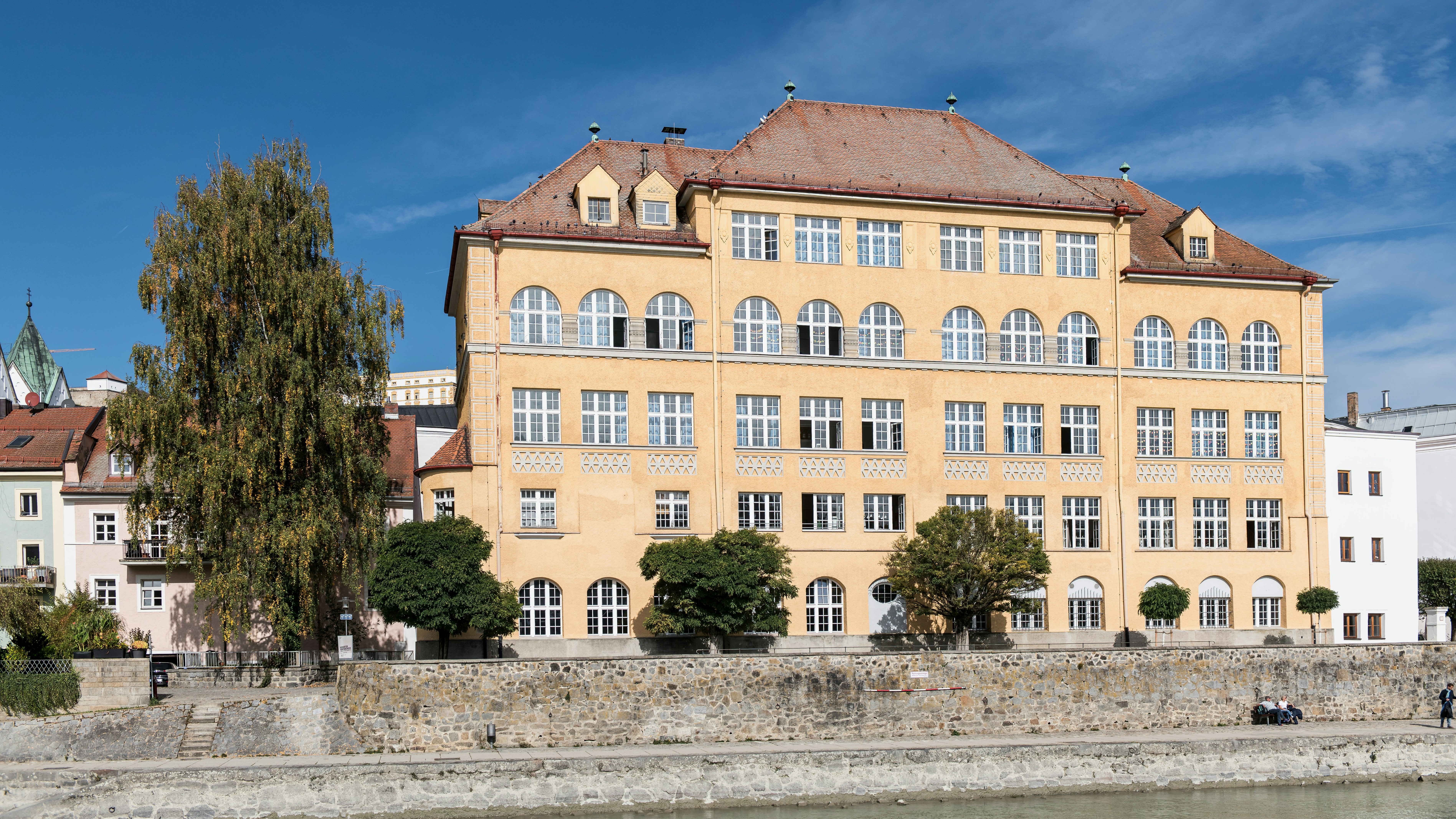 Large yellow building on a riverbank under blue sky