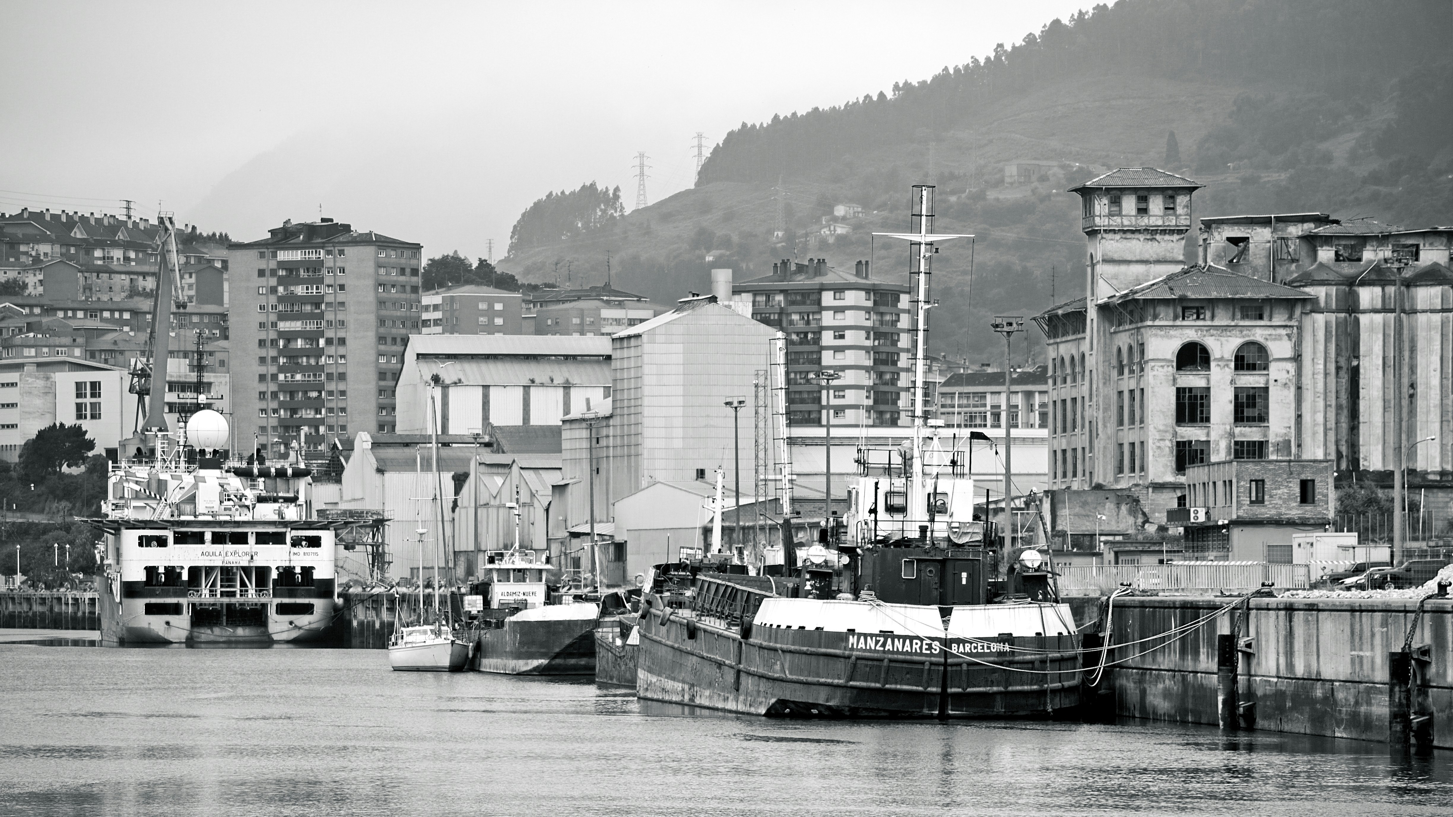 Barcos atracaram em um porto com prédios da cidade atrás.
