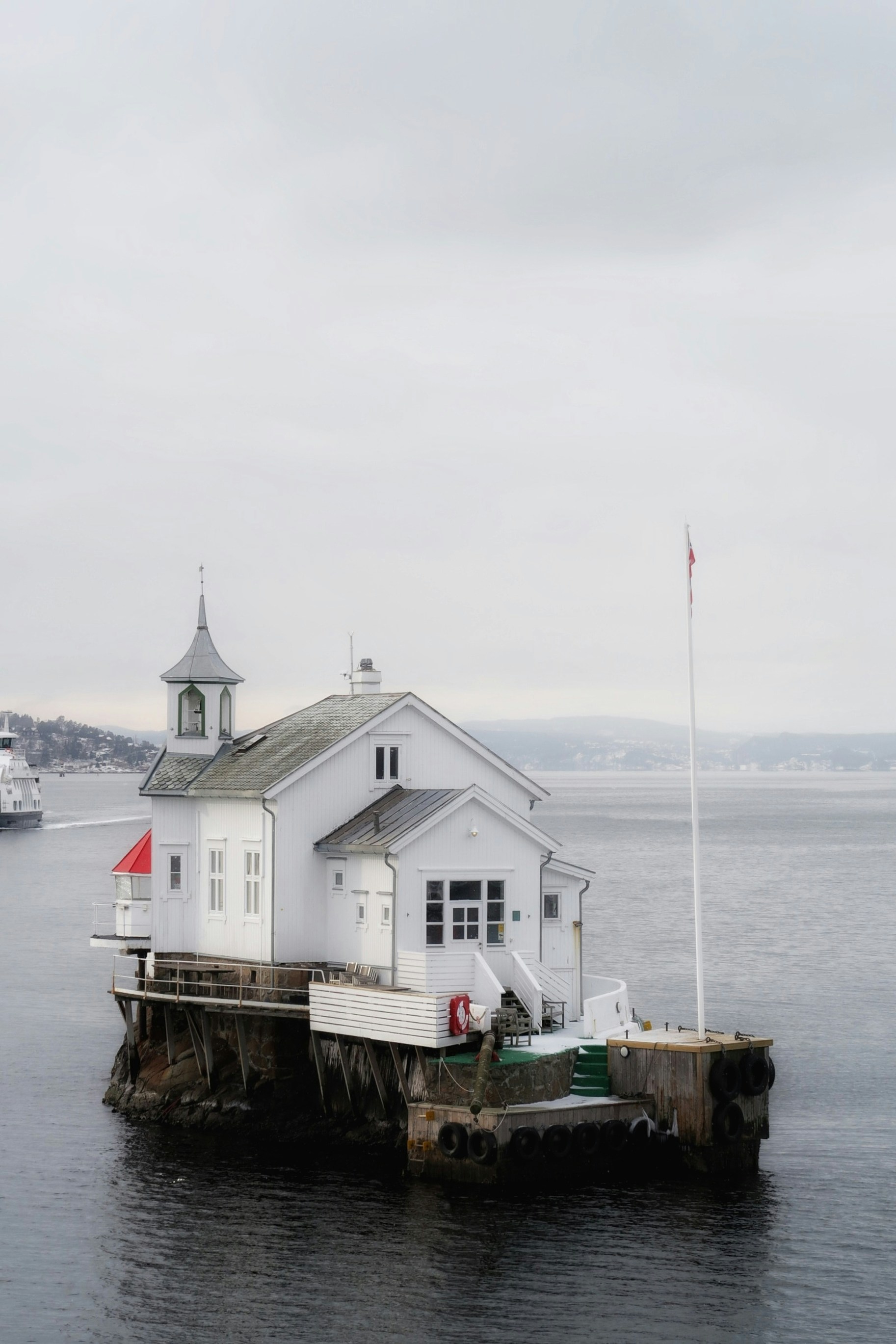 Small white building on a rocky island in the water.