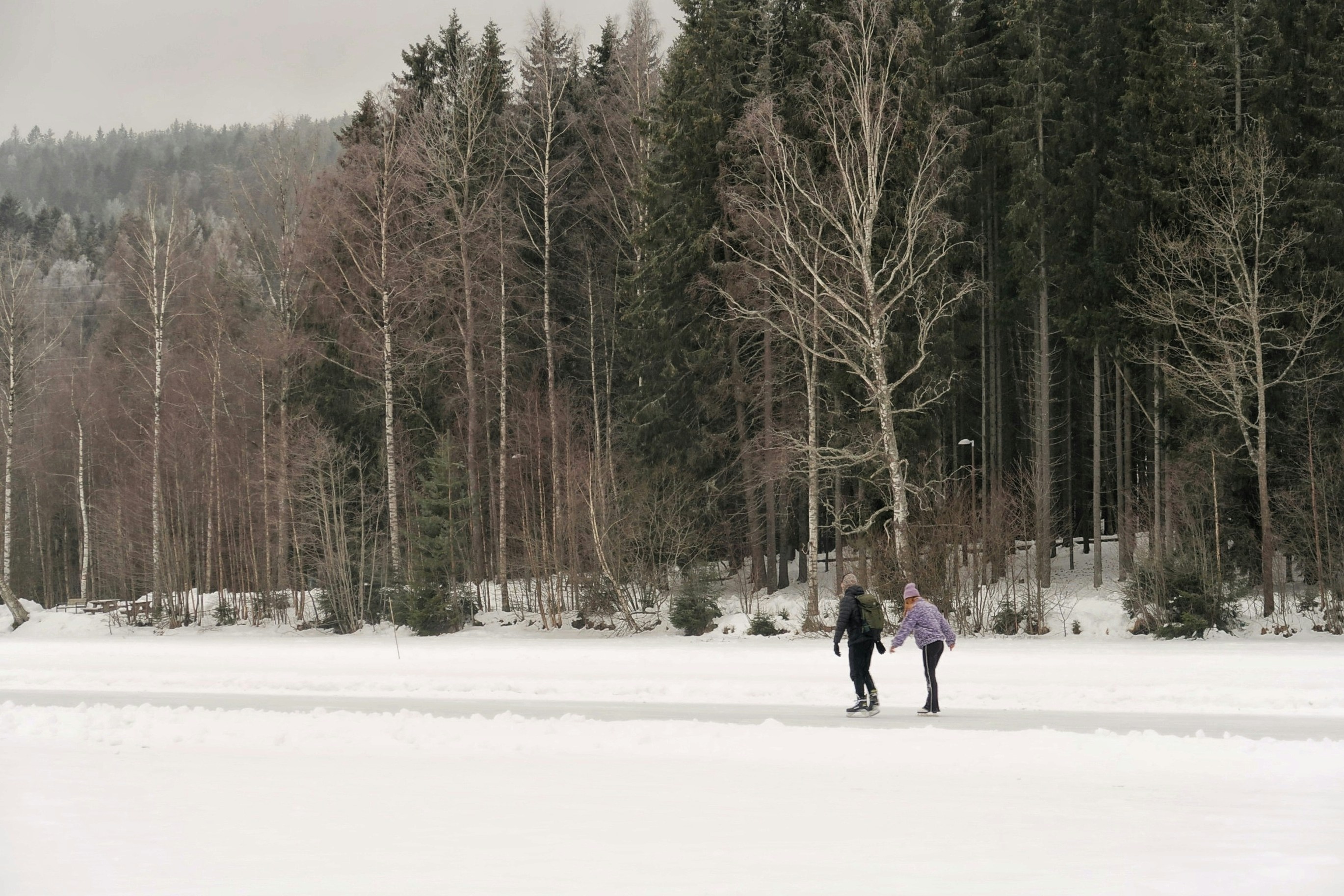 Two people ice skating on a frozen lake