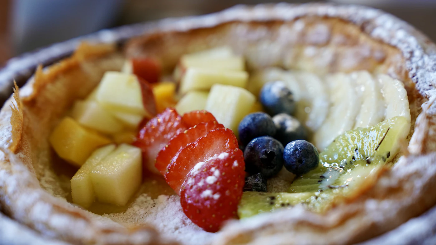 Puffed Dutch baby pancake in a skillet topped with fresh berries