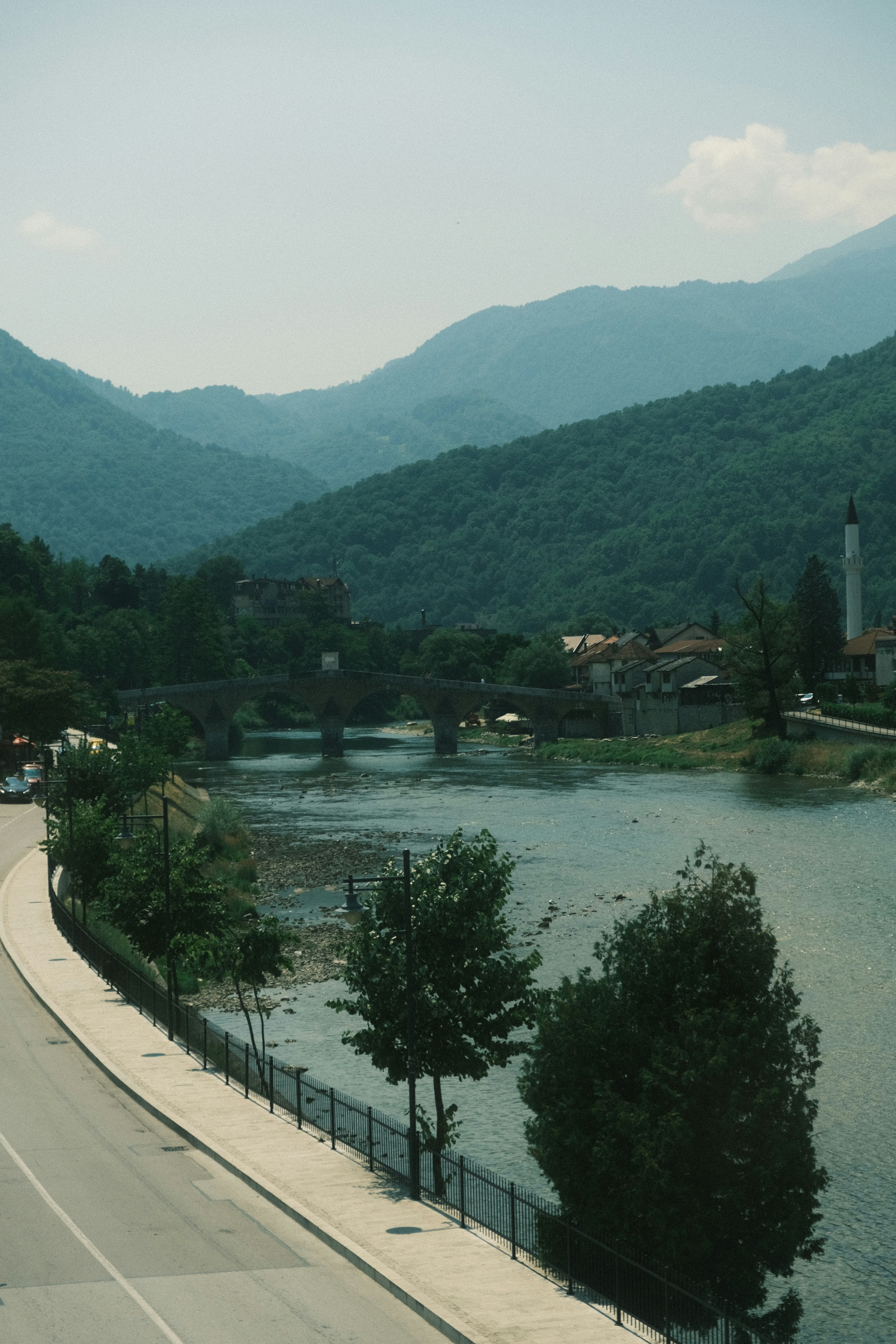 River flows past a town with a bridge and mosque.