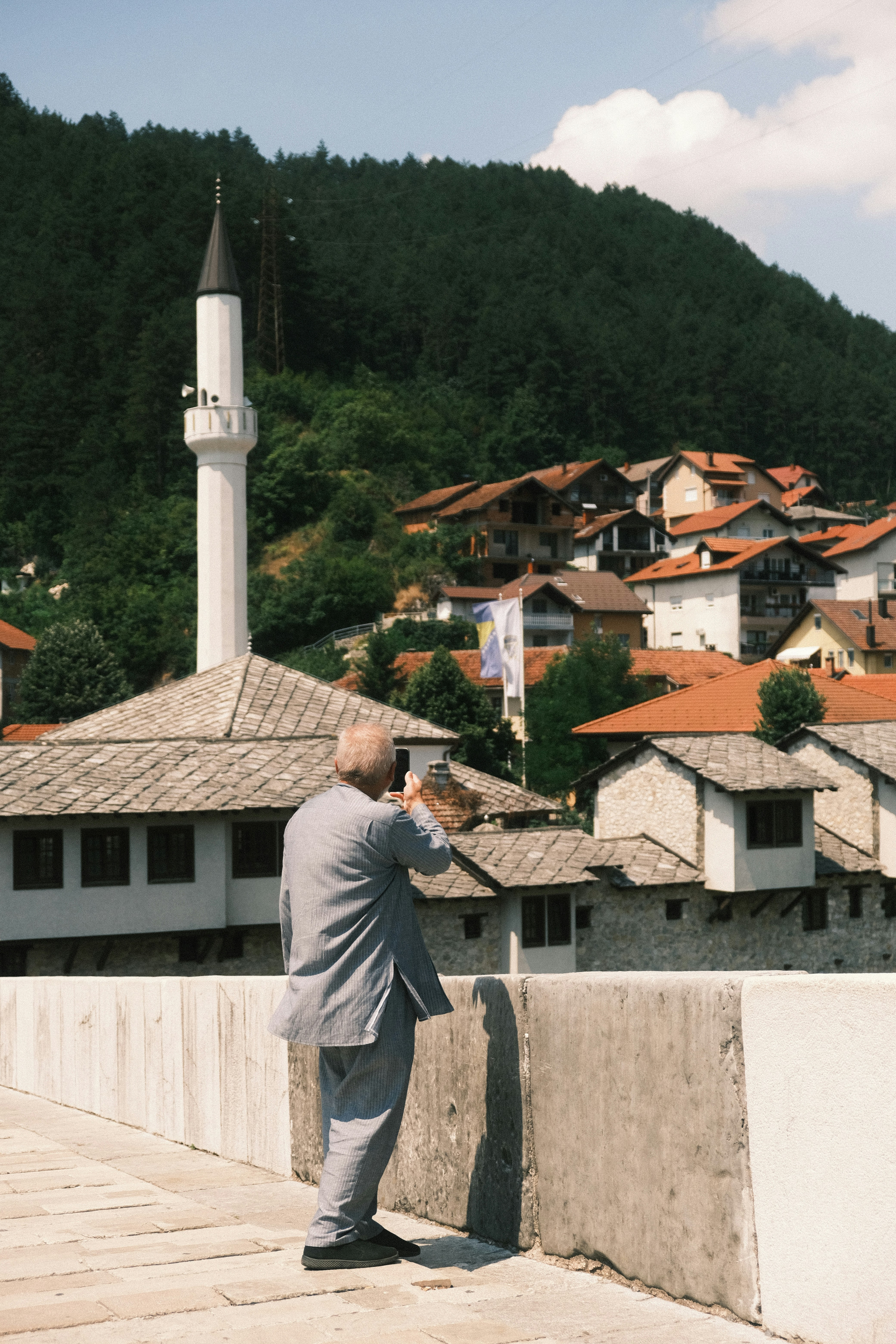 Man in suit on bridge overlooking historic town