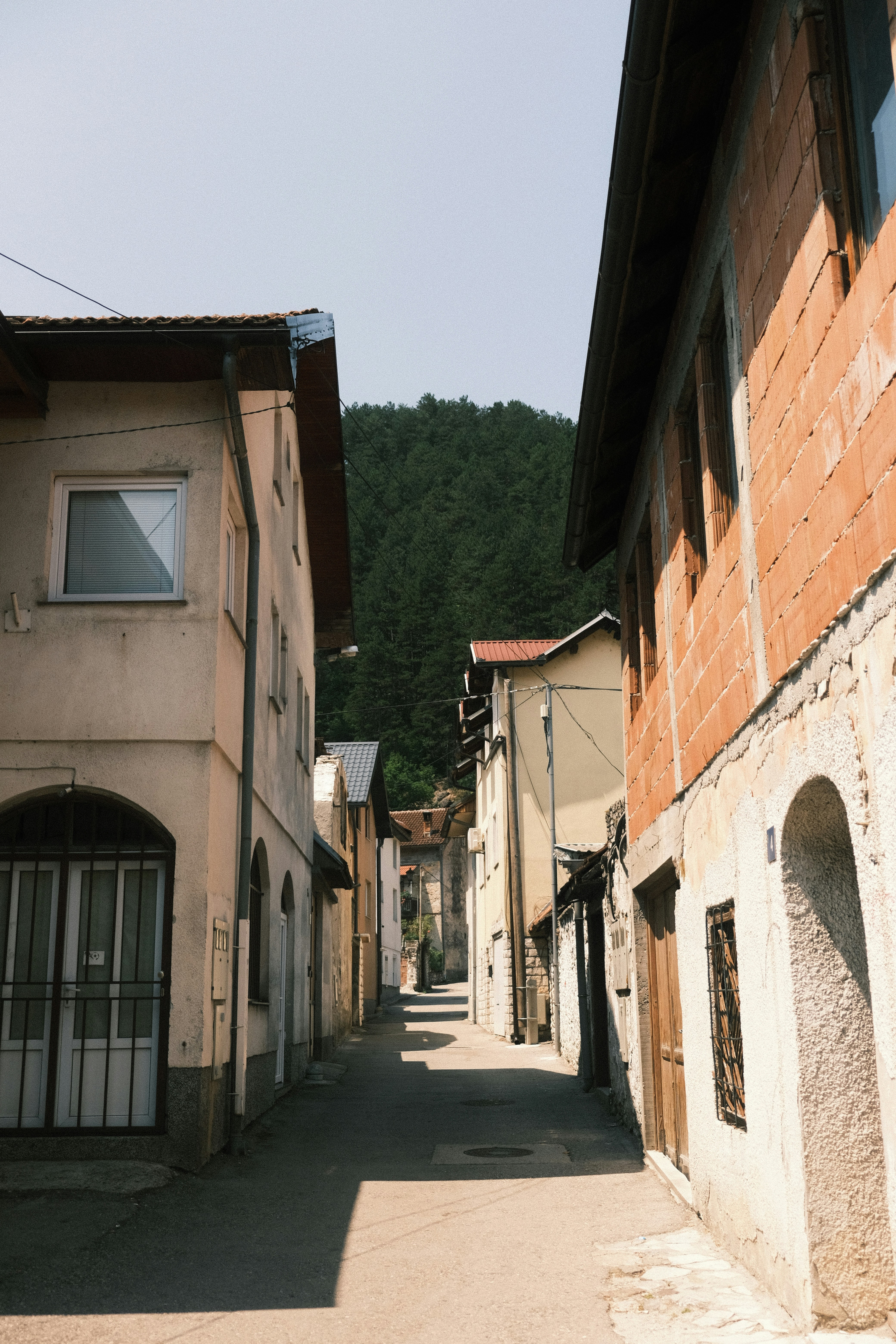 Narrow street between old buildings with trees beyond