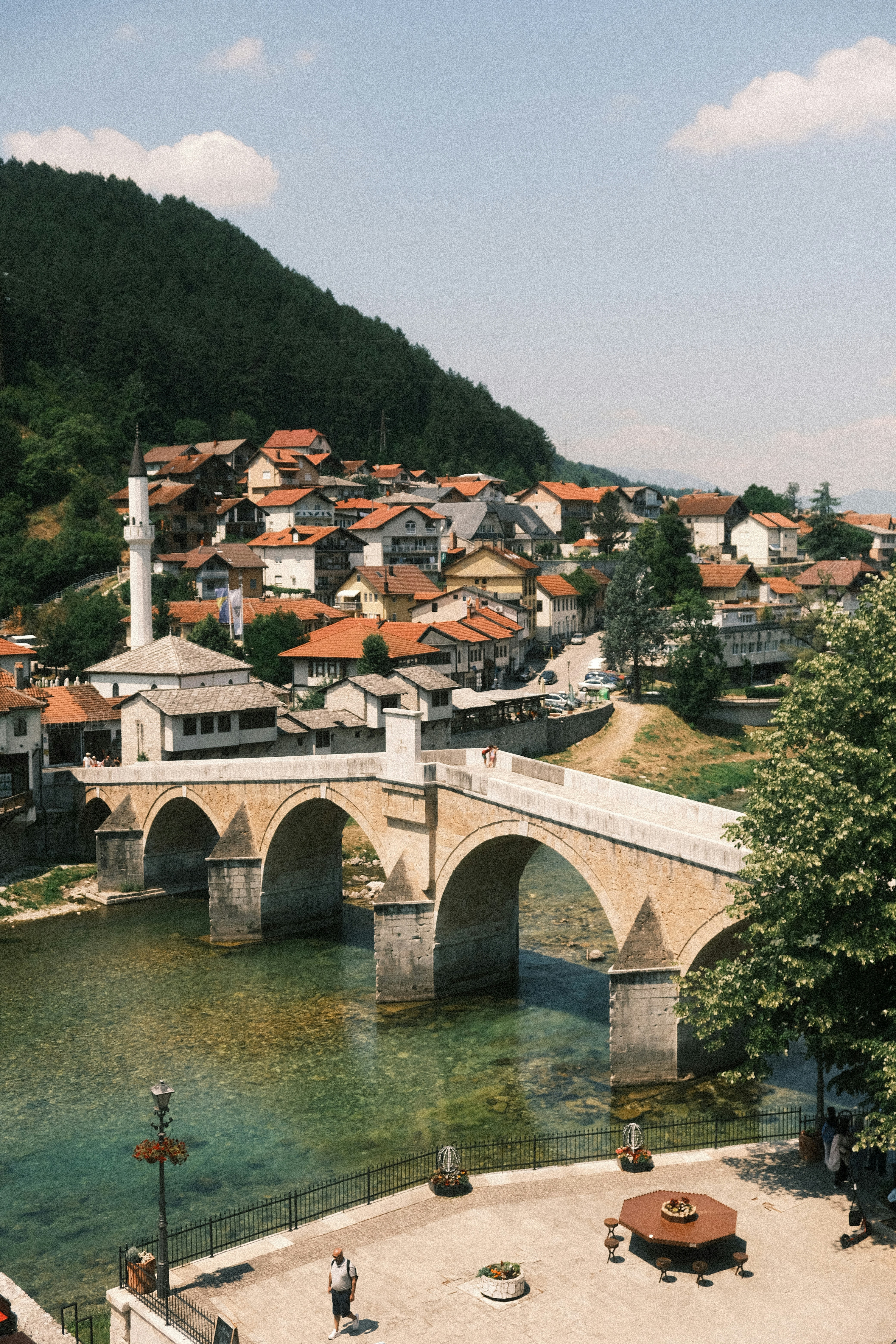 Stone bridge over a clear river with a town behind