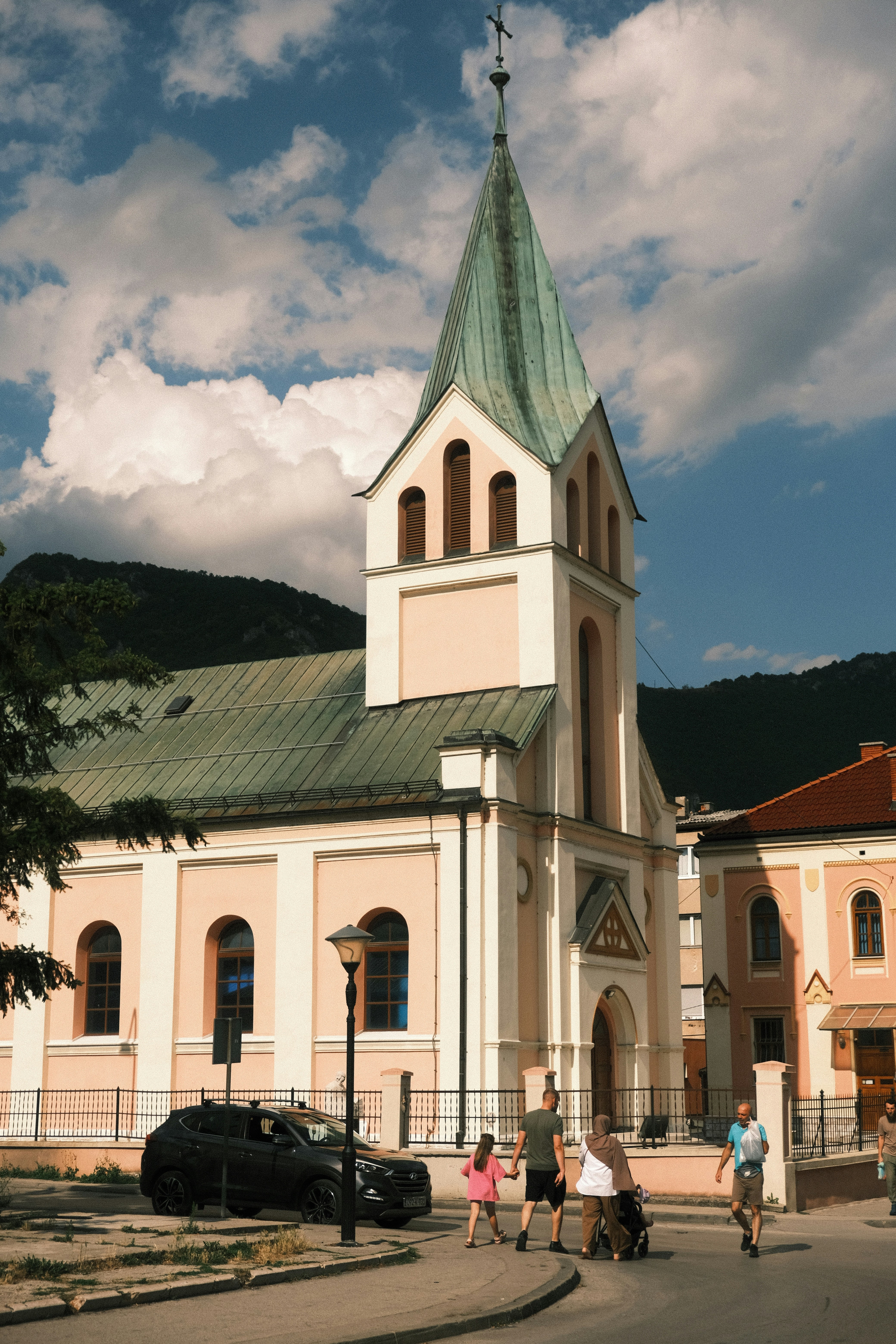 A church with a tall steeple and people walking outside.