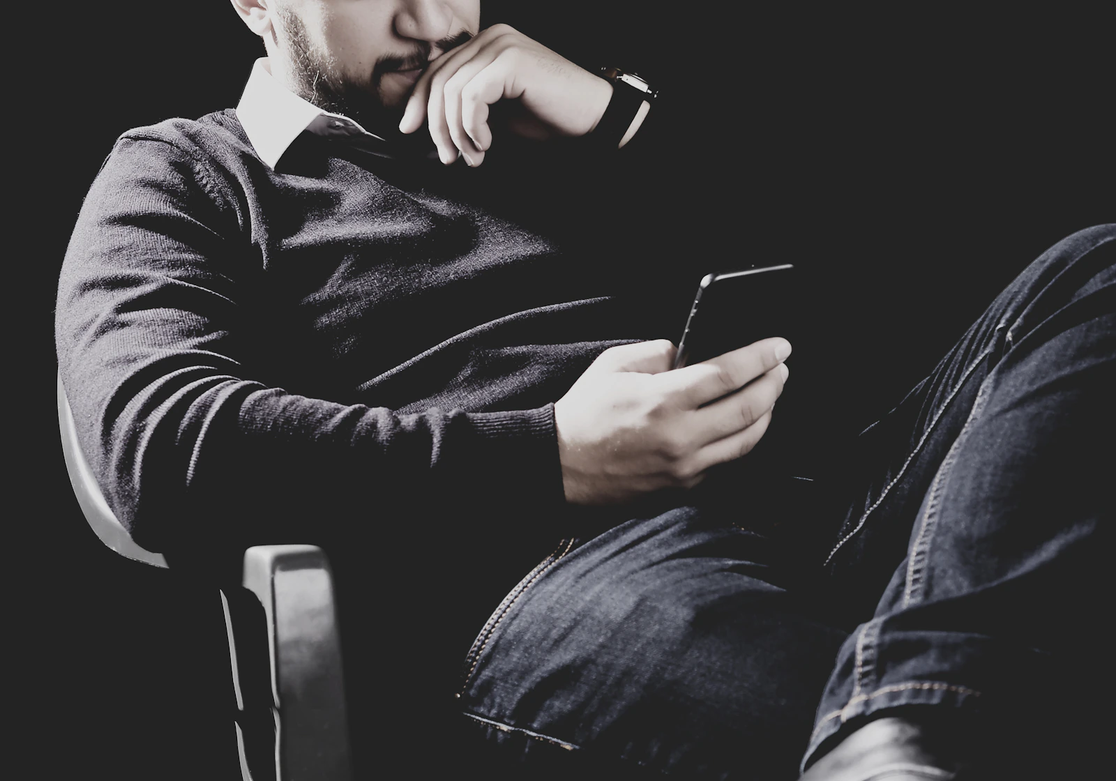 Man sitting alone and looking at his phone after receiving a difficult relationship message