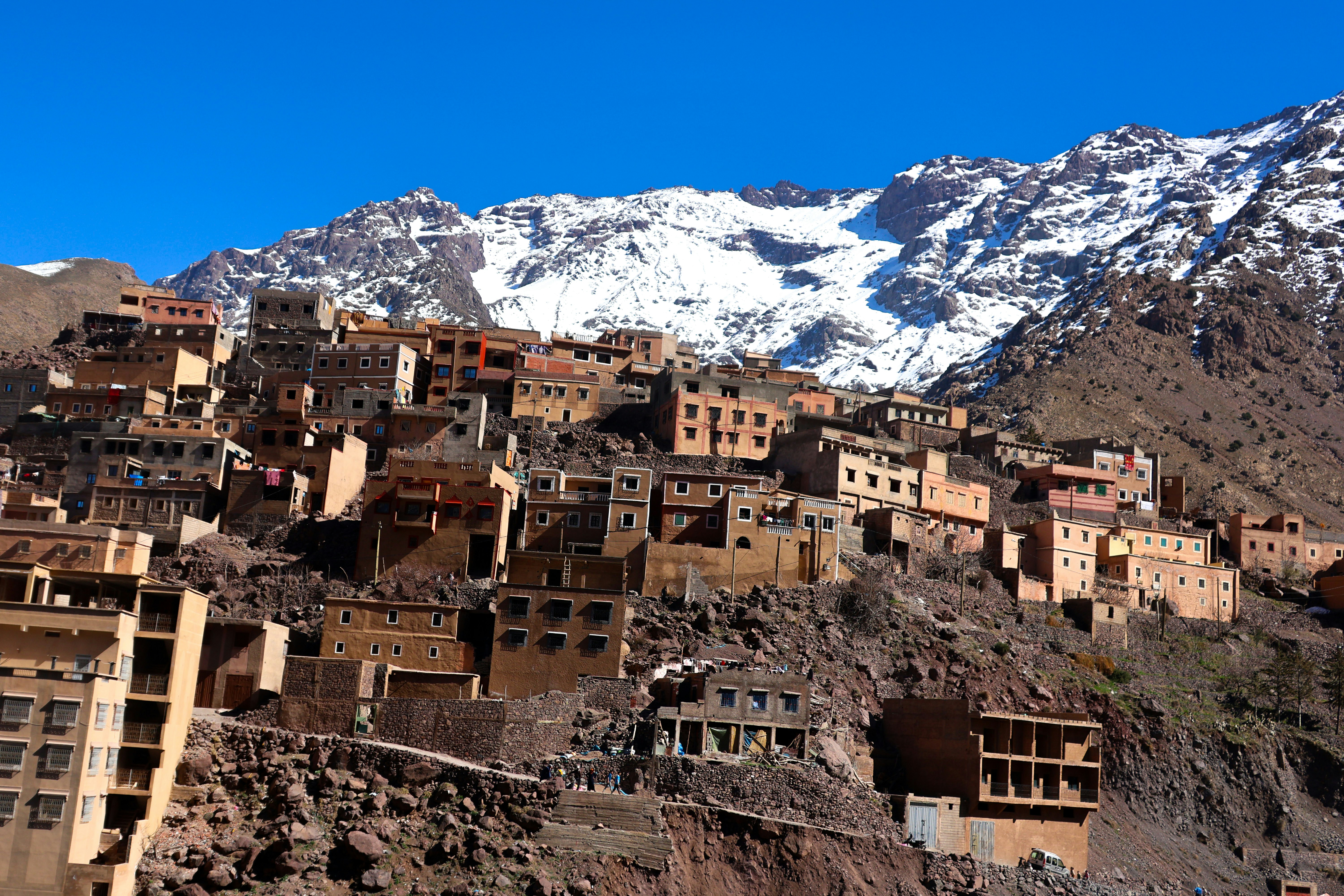 Un pueblo tradicional enclavado en una ladera con picos nevados.