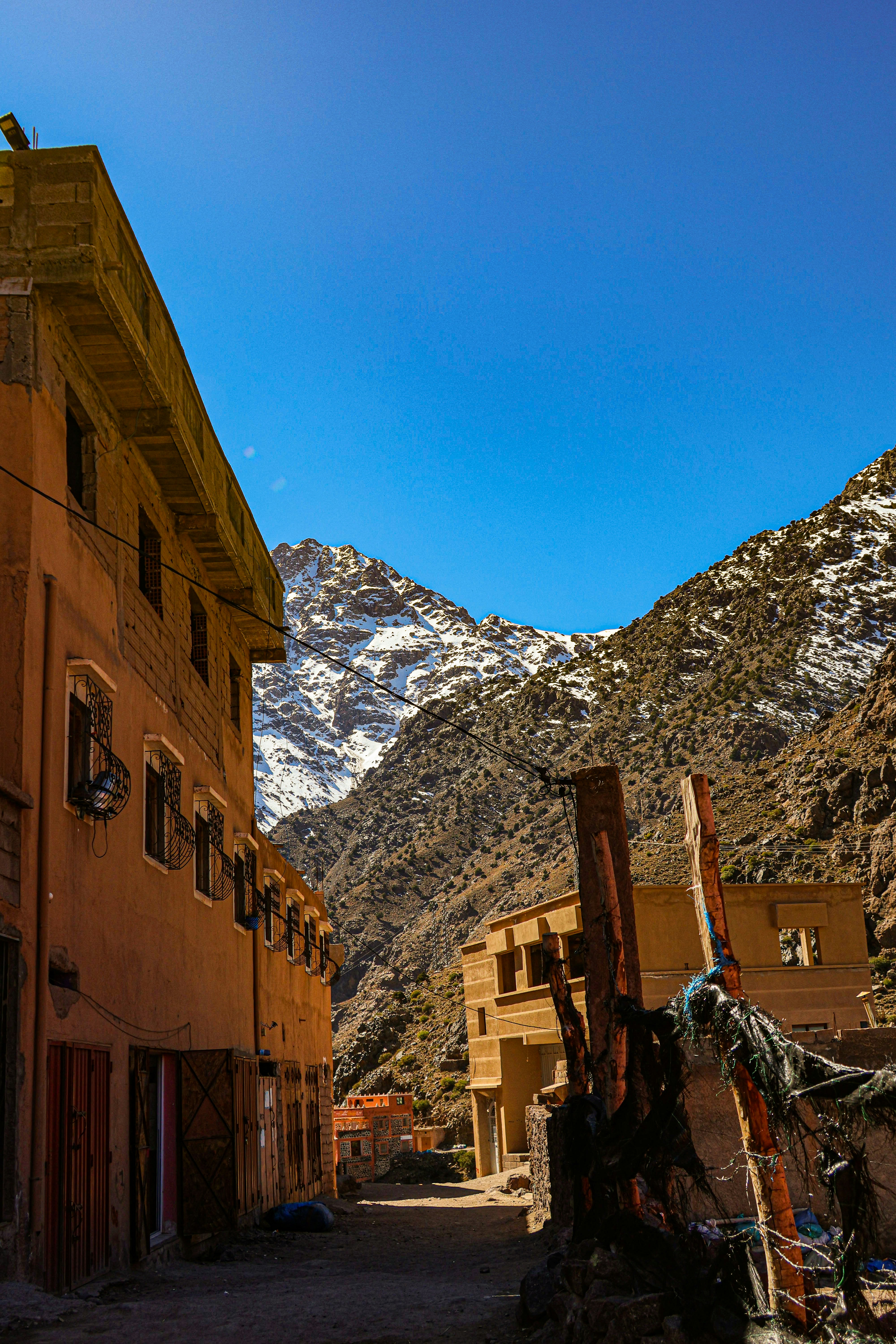 Una calle estrecha entre edificios con montañas nevadas más allá