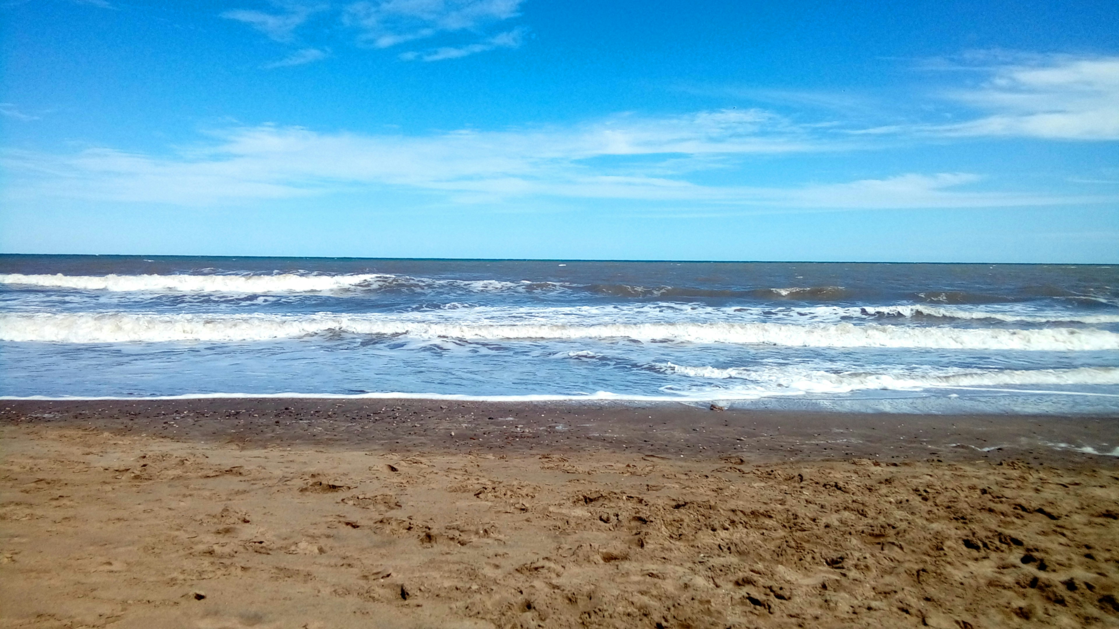 Sandy beach with ocean waves under a blue sky