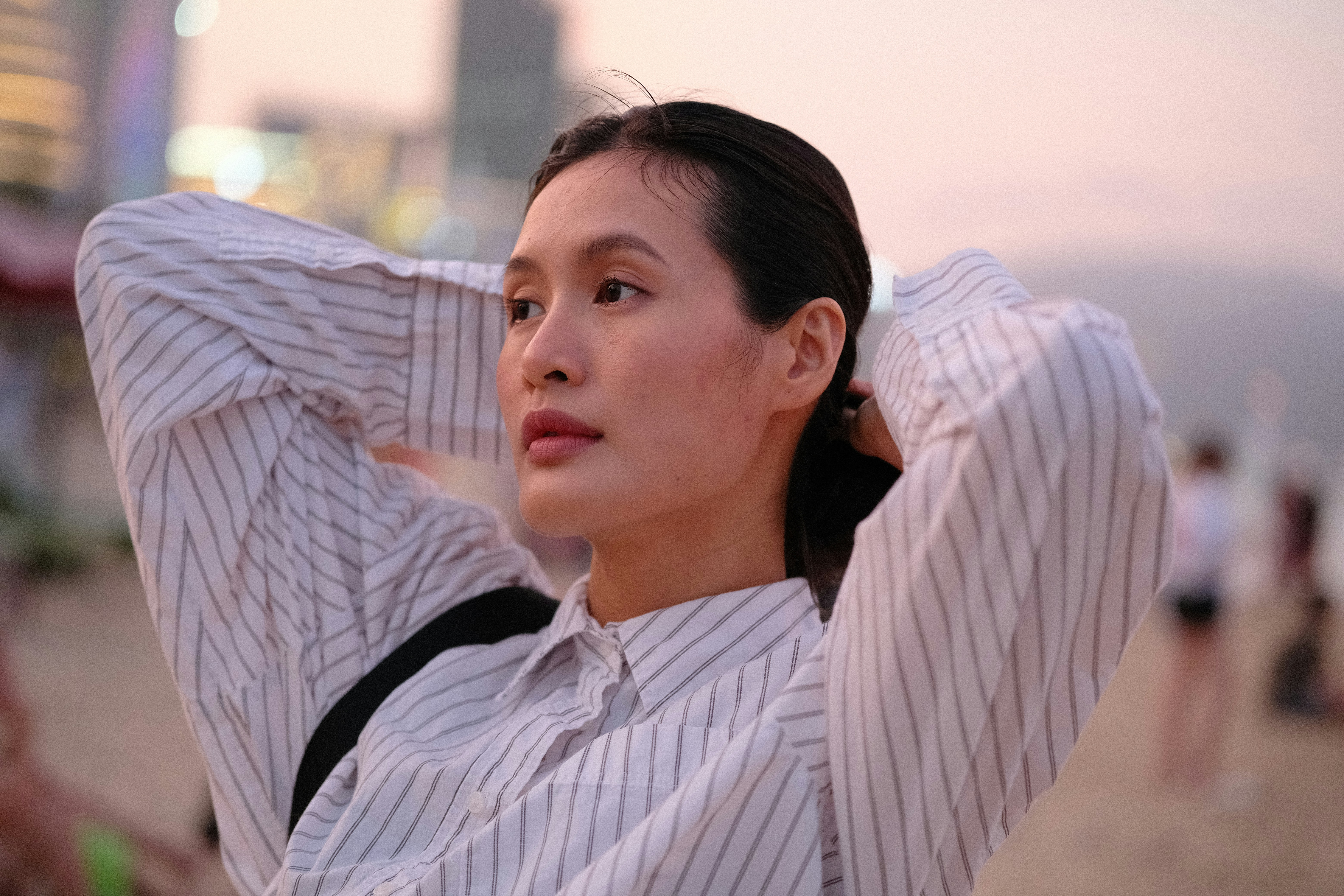 Woman with hands in hair on beach at sunset