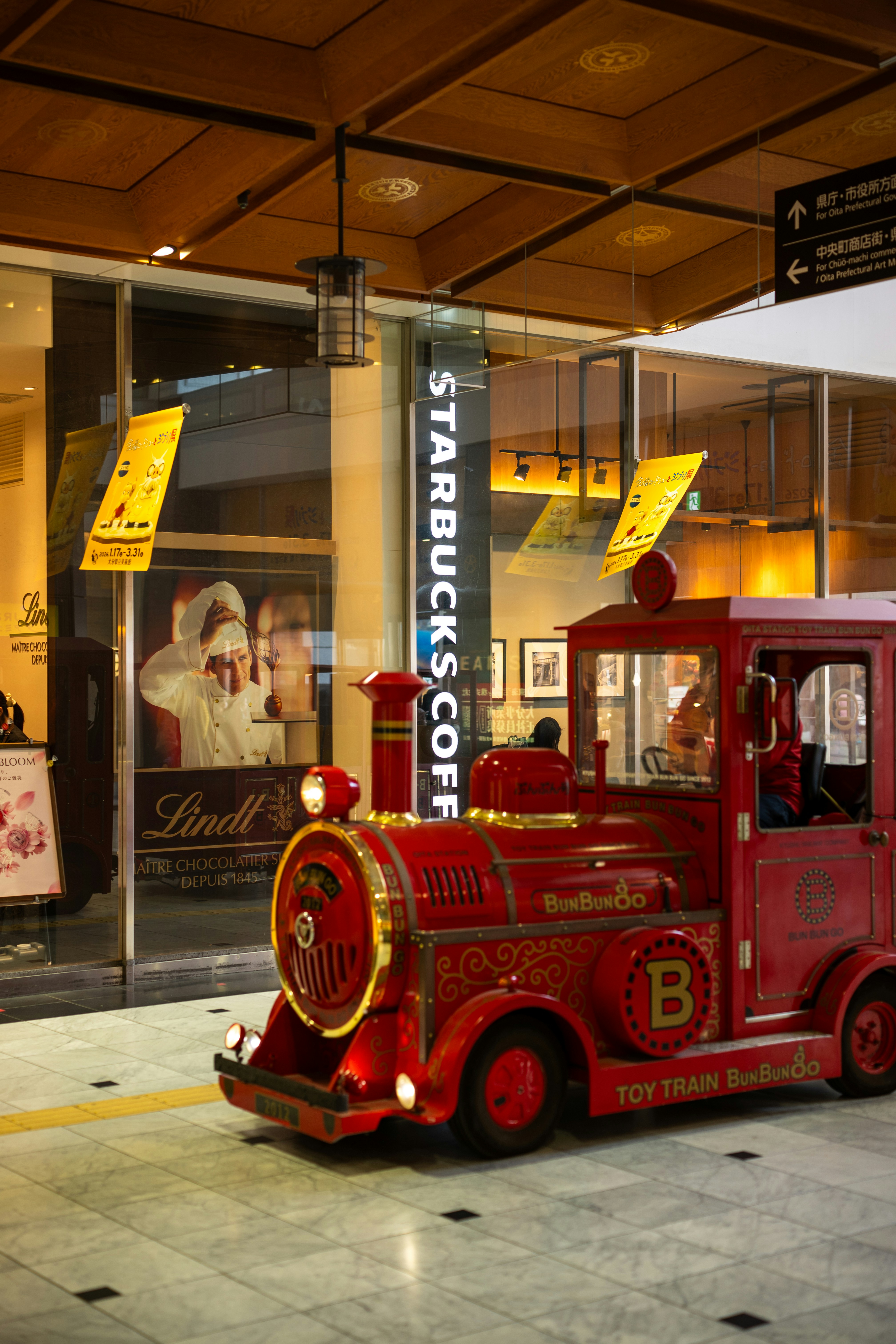 Ein kleiner roter Spielzeugzug vor einem Starbucks.