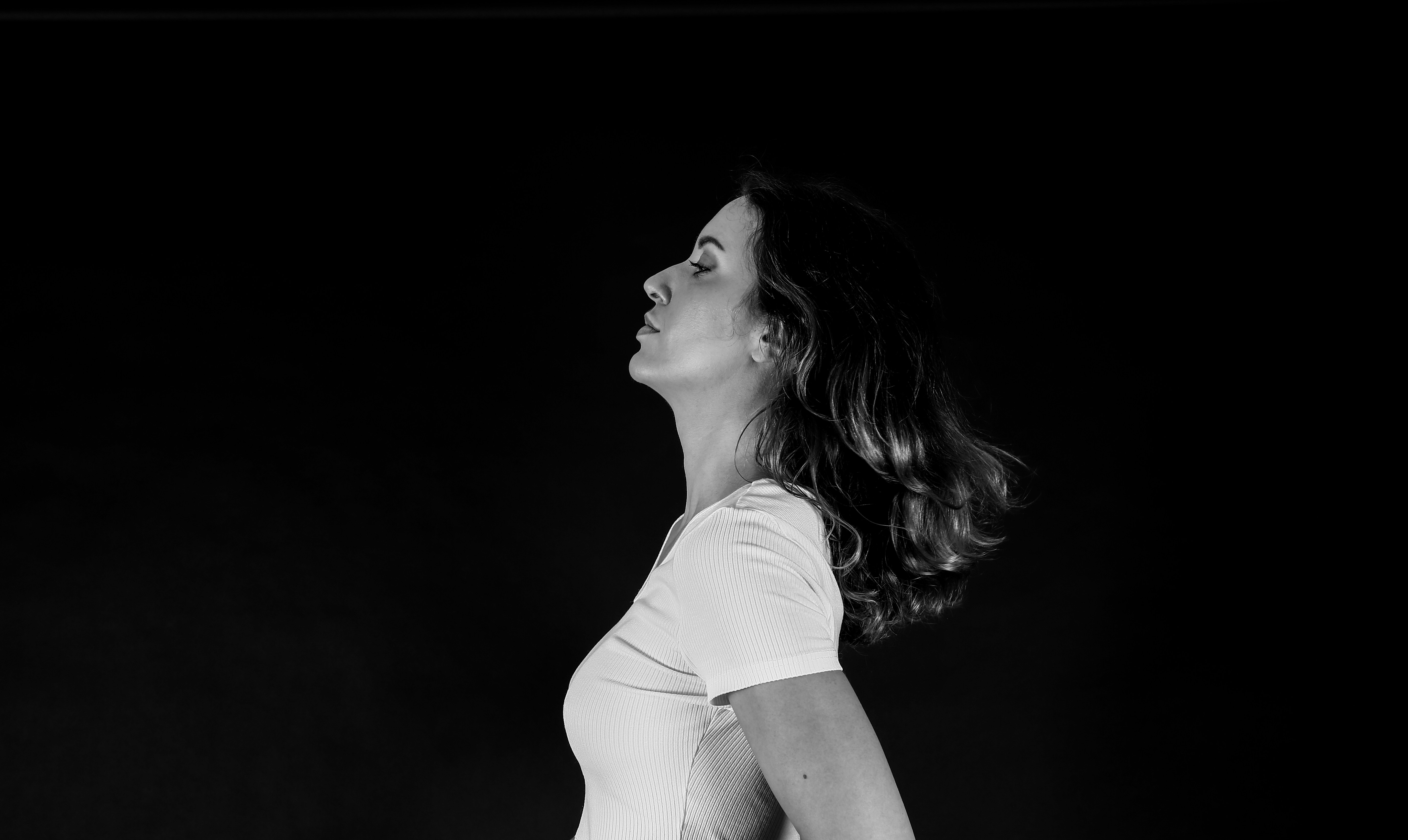 Woman with hair blowing against a black background