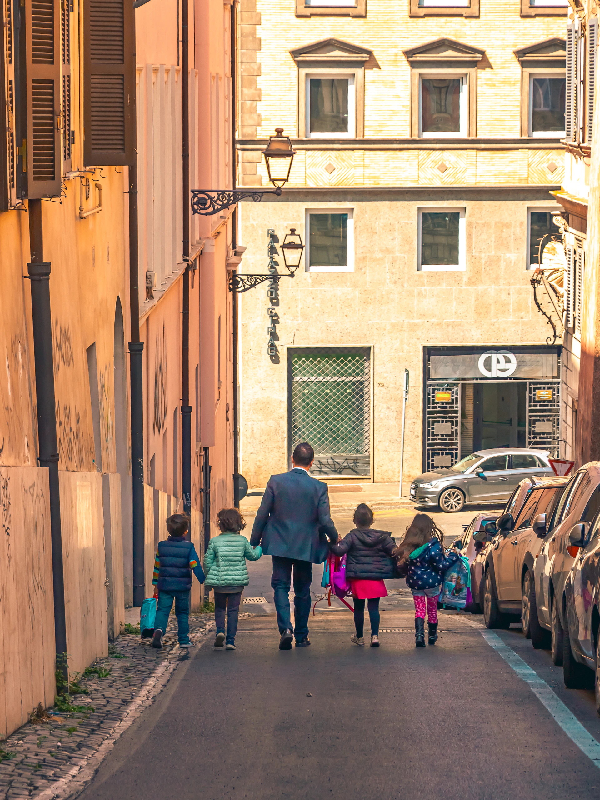Man walks with four children down narrow street.