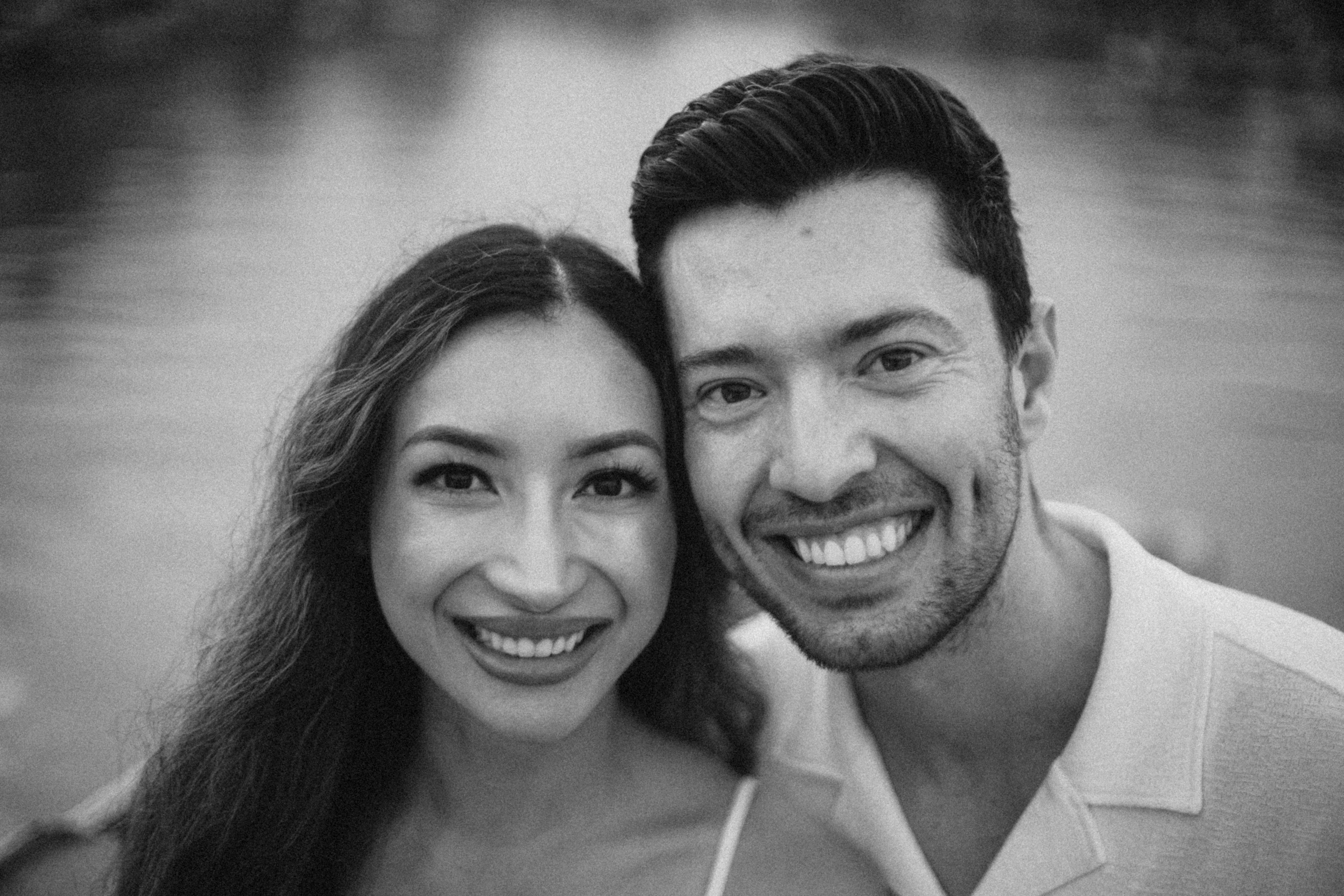 A smiling couple poses for a black and white portrait.