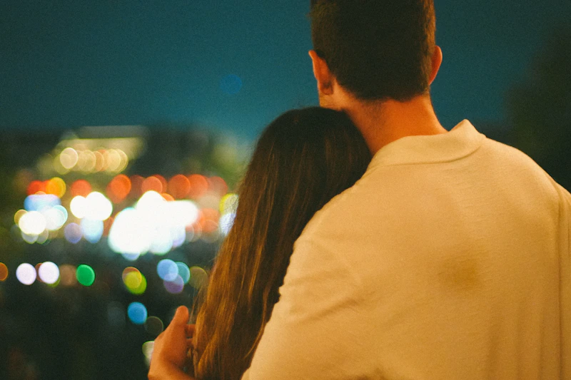 Couple embracing at night with city lights background