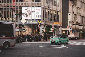 Green car drives past starbucks and tsutaya stores.