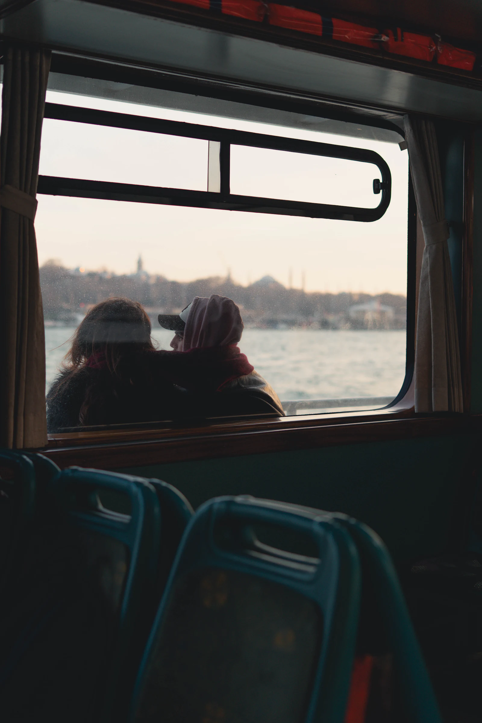 Two people looking out of a ferry window at the city