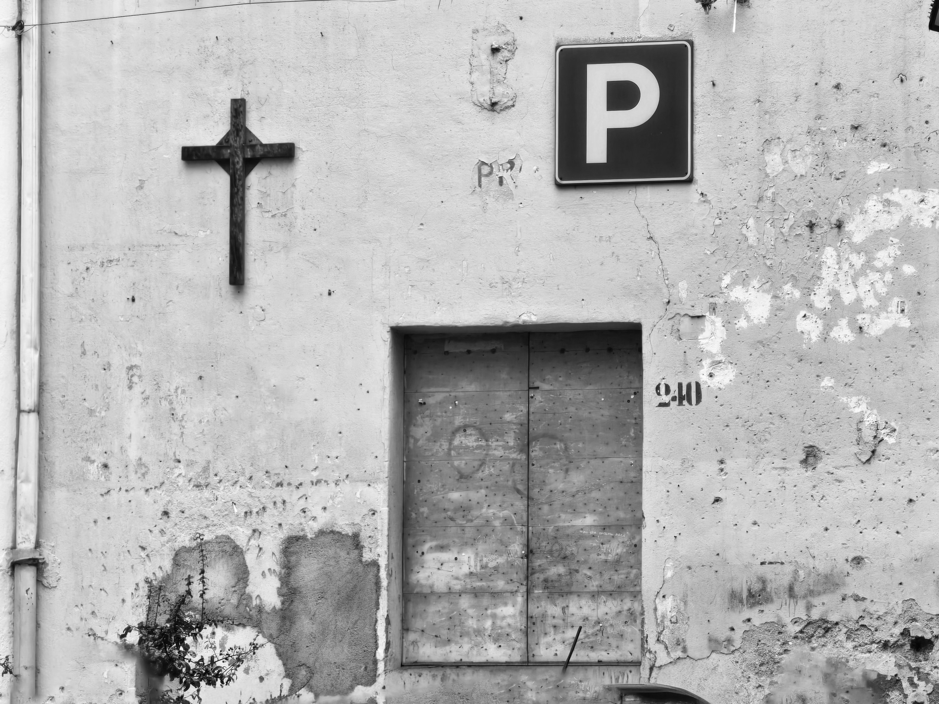 A crucifix and parking sign on a weathered wall.