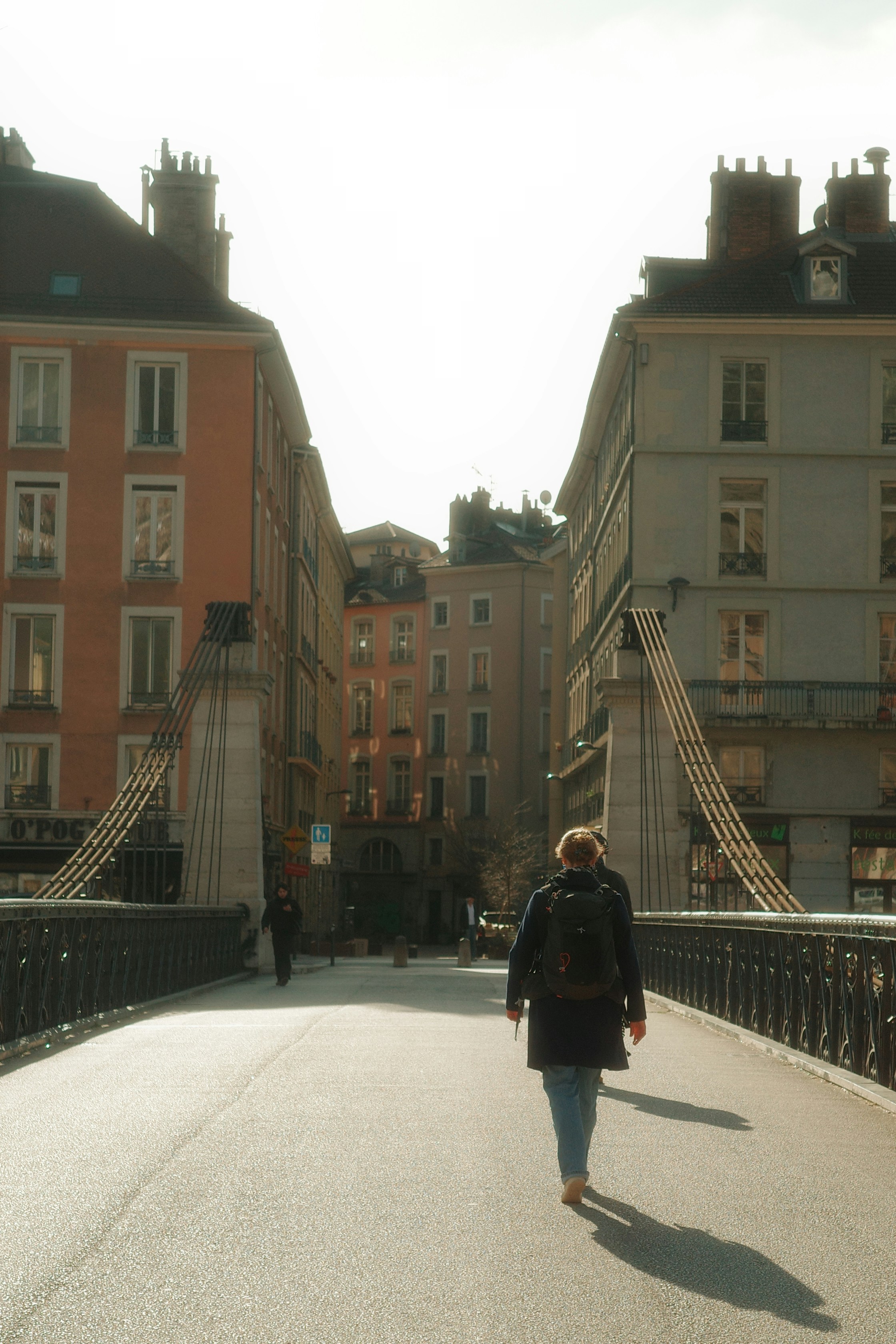 Woman walking across a bridge between buildings.