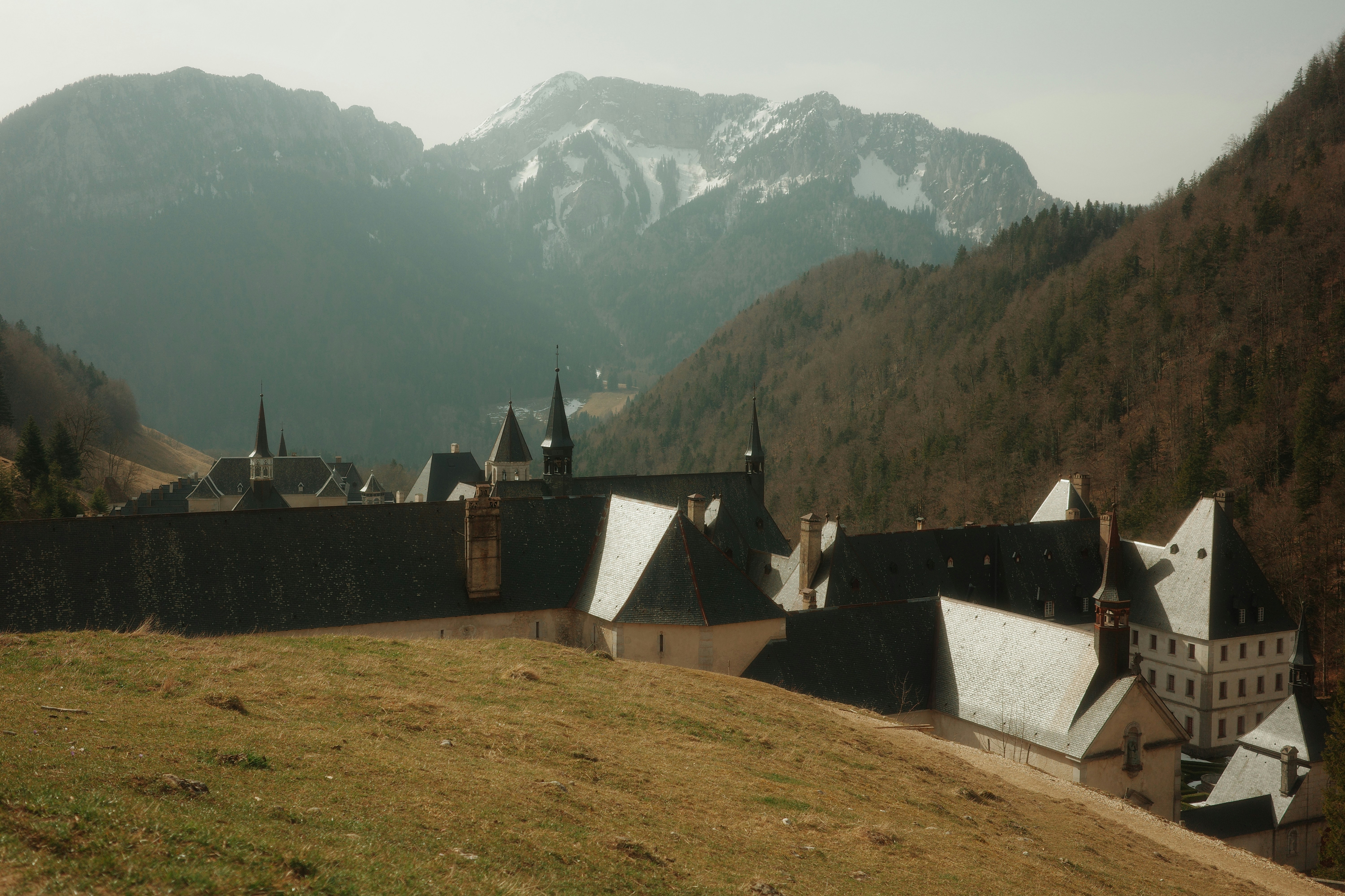 Monastery nestled in a mountain valley with snow-capped peaks.