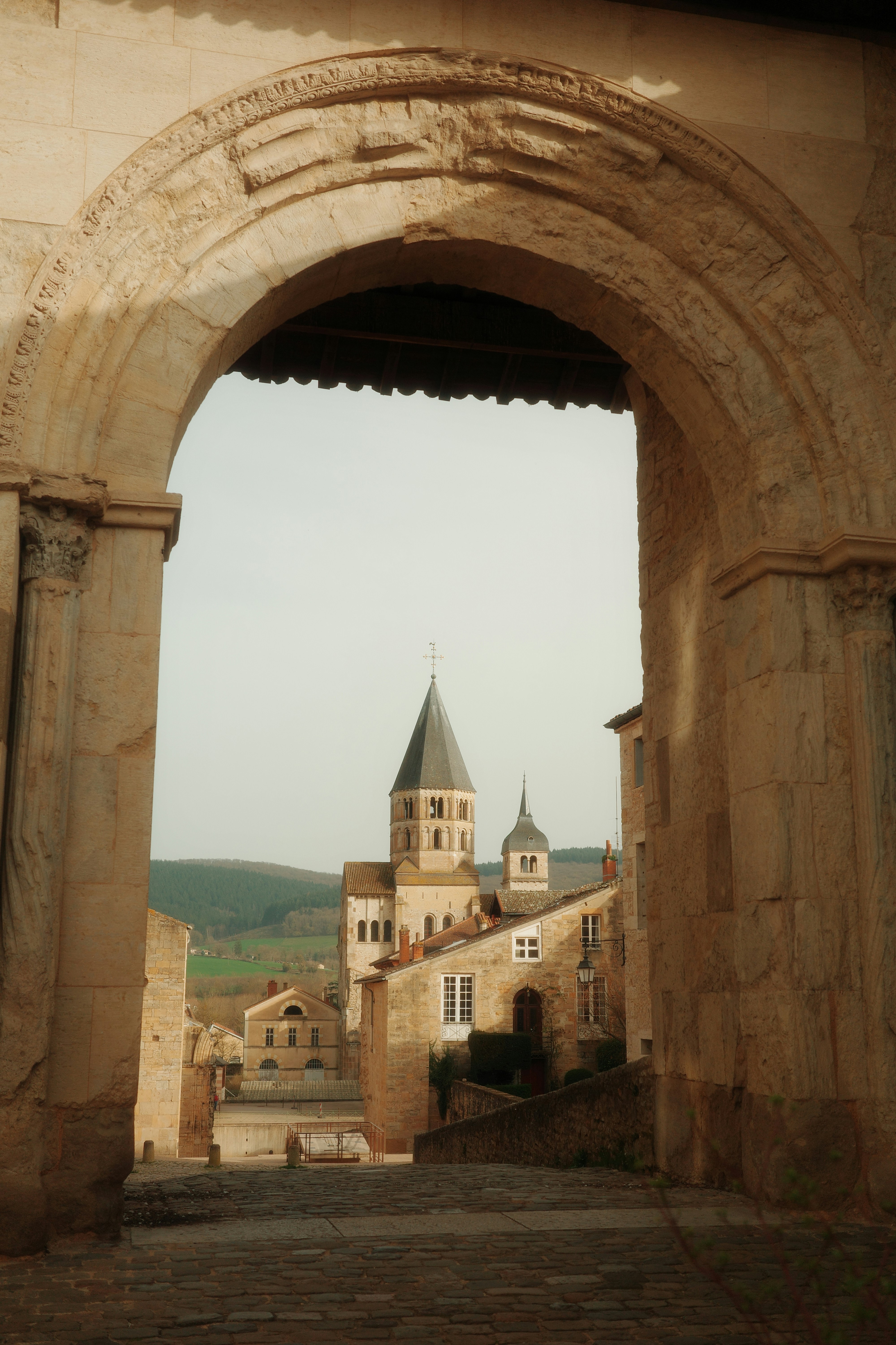 View through an archway to historic buildings and church tower.
